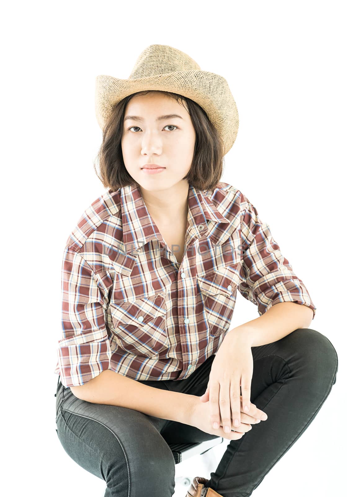 Young pretty woman in a cowboy hat and plaid shirt posing in studio with isolated on white background