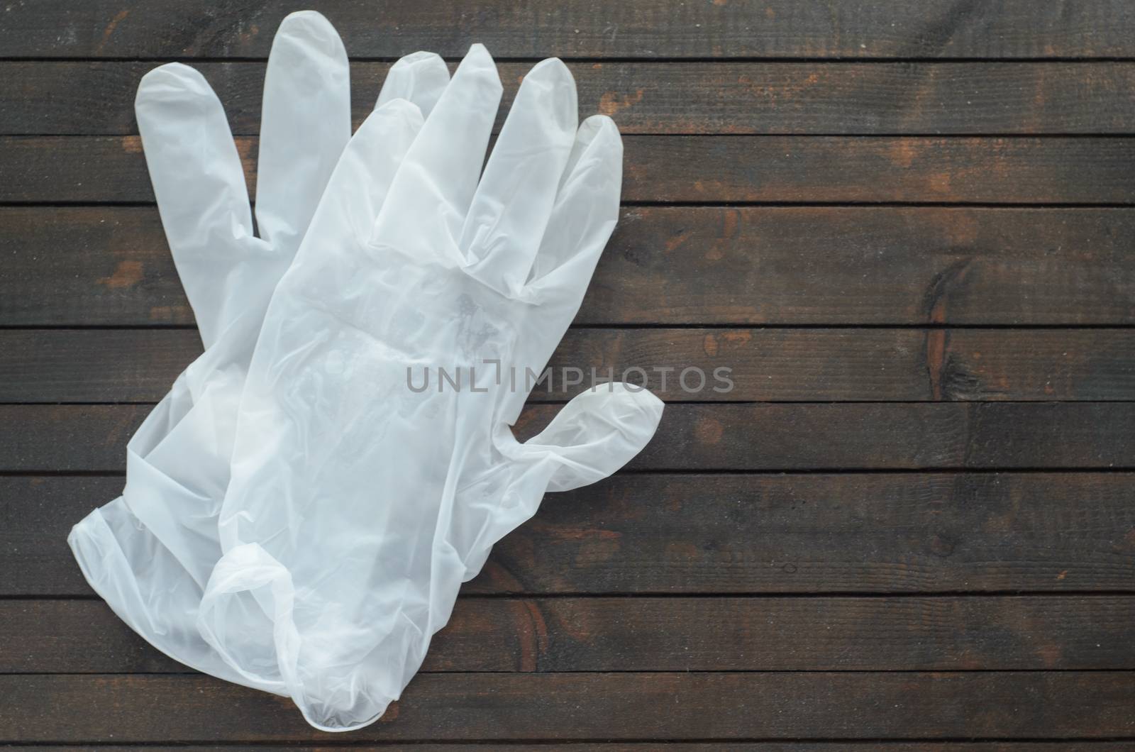 White disposable gloves on dark wooden background.Gloves for protection against coronavirus. by andre_dechapelle