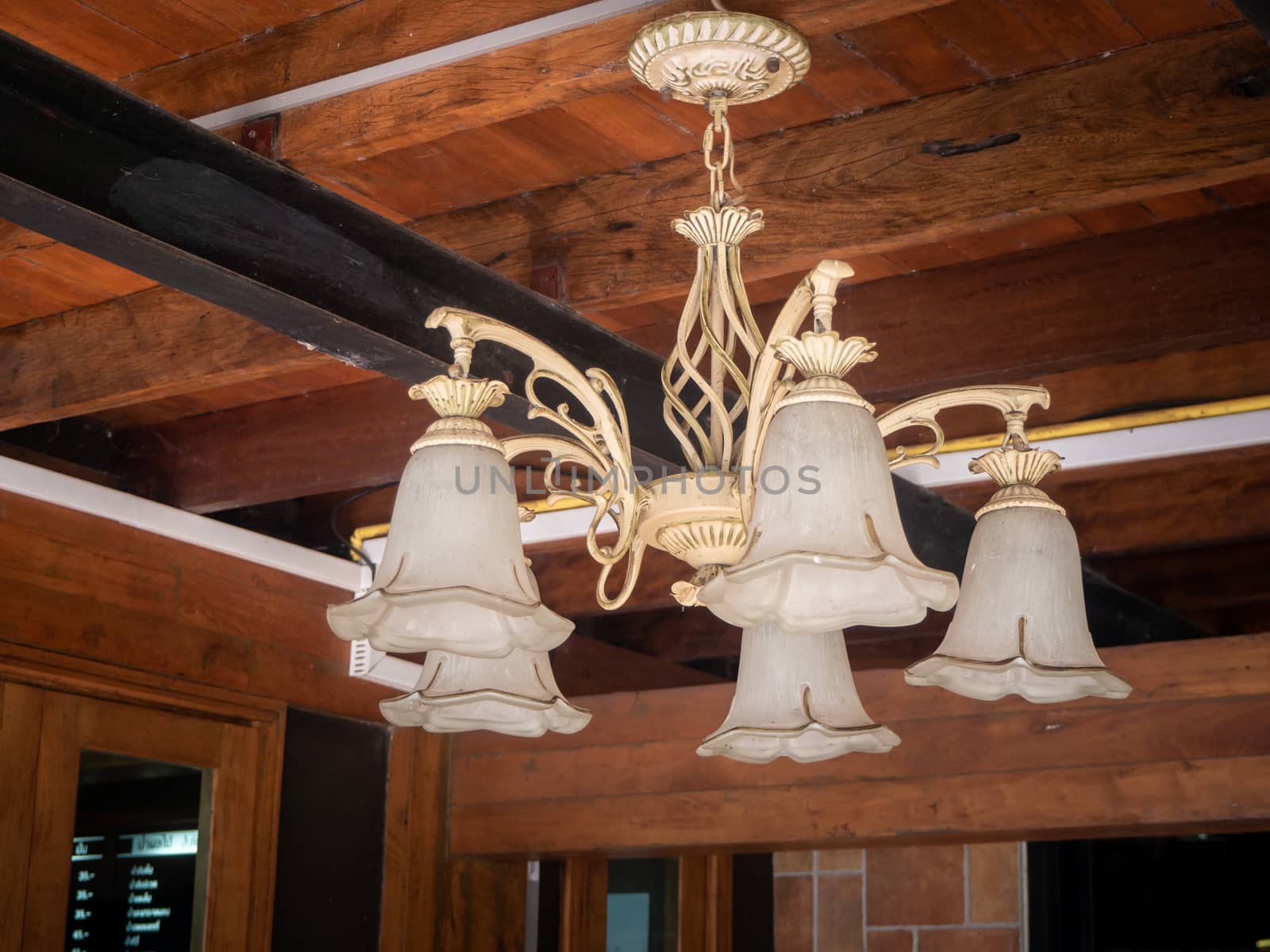 beautiful vintage interior background of a lighted retro chandelier hanging on a wooden ceiling, decorated lamp with flowers