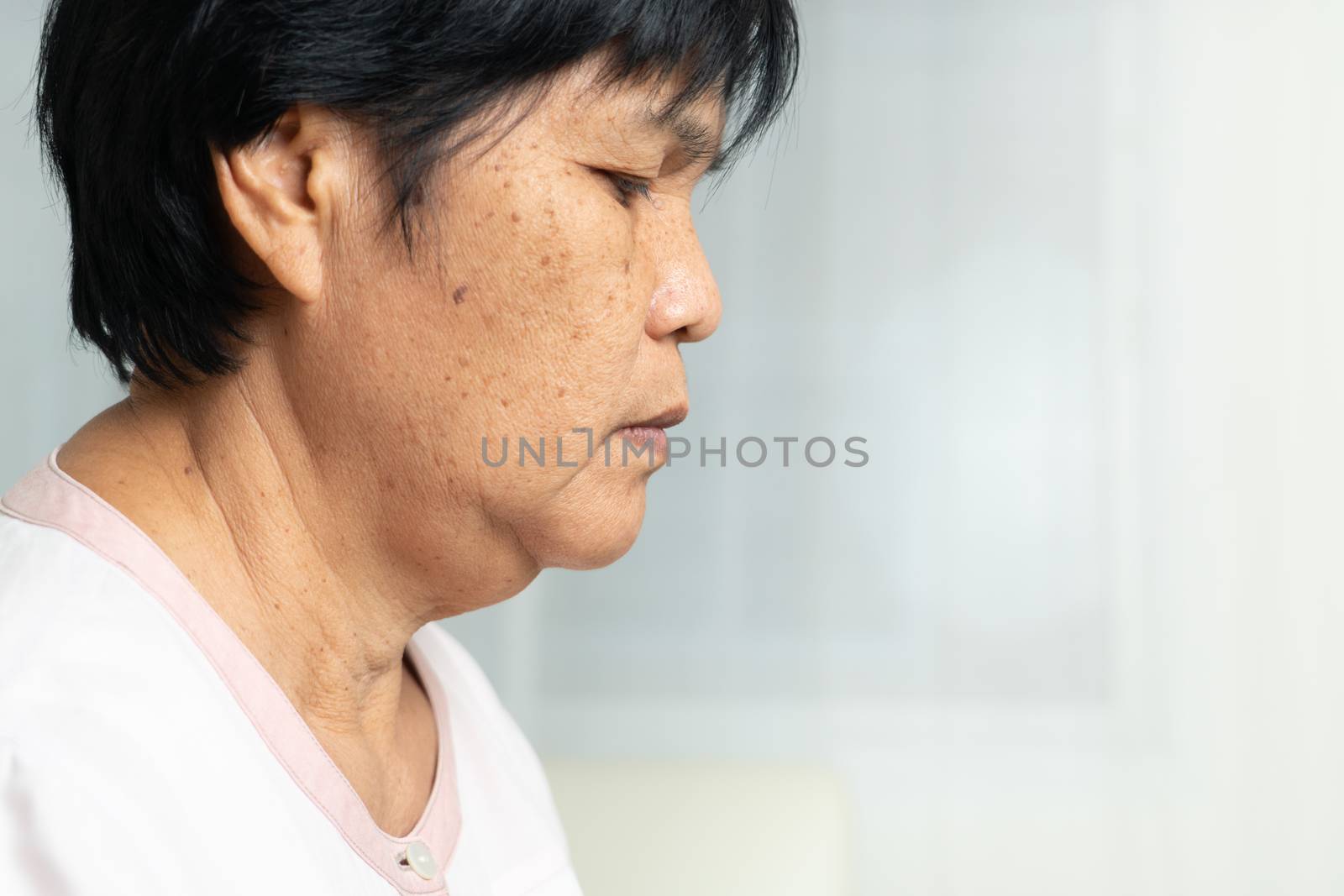 Close-up of Asian elder woman face with wrinkled skin condition. side view