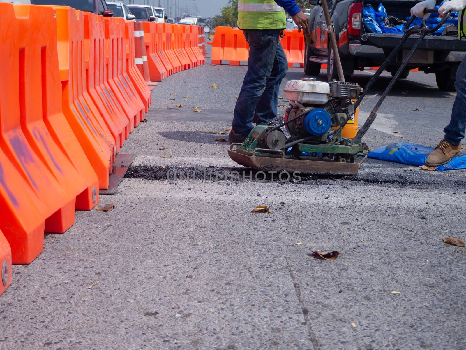 Worker use vibratory plate compactor compacting asphalt at road repair