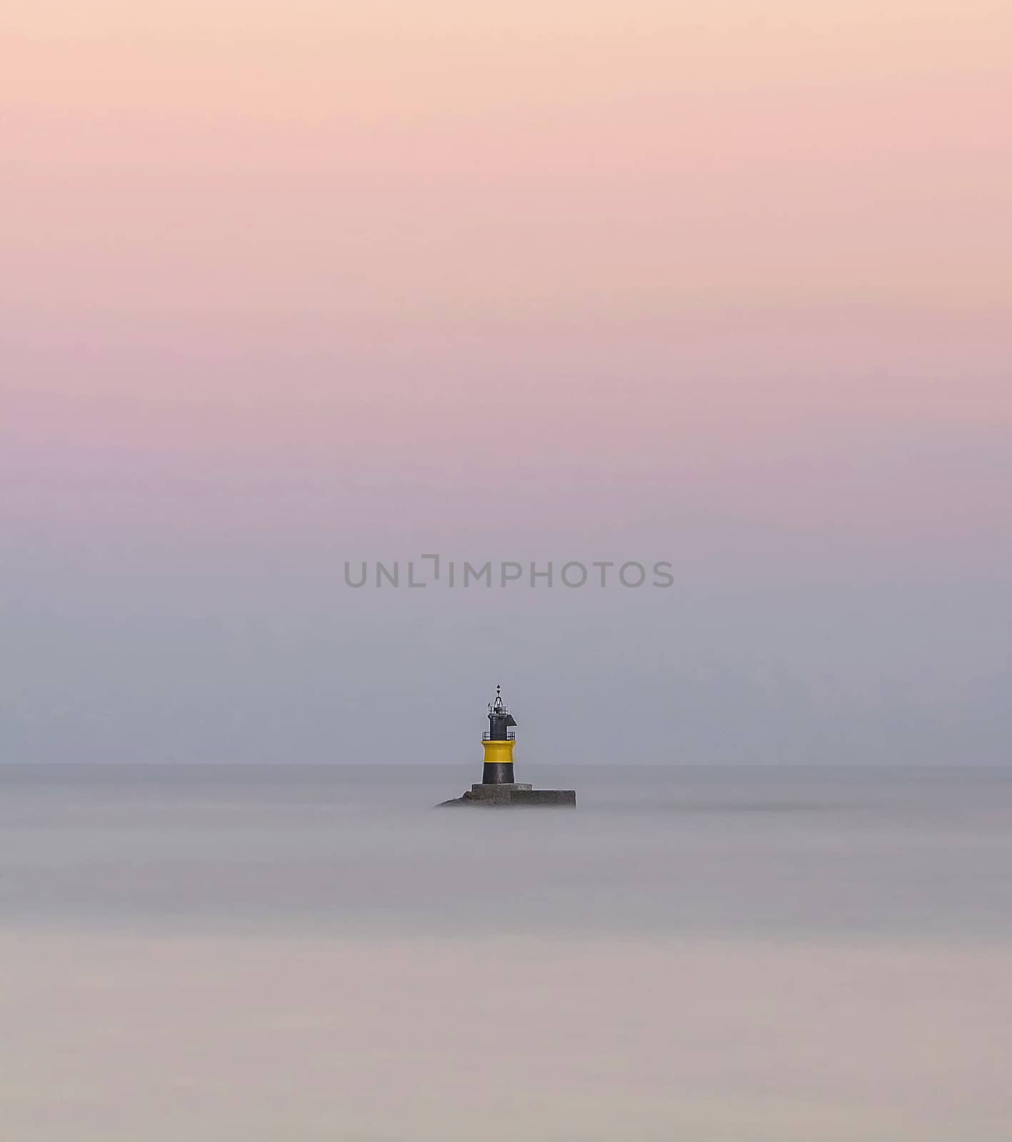 Lighthouse of Burela, Spain surrounded by the sea with silky effect and sky in pastel tones