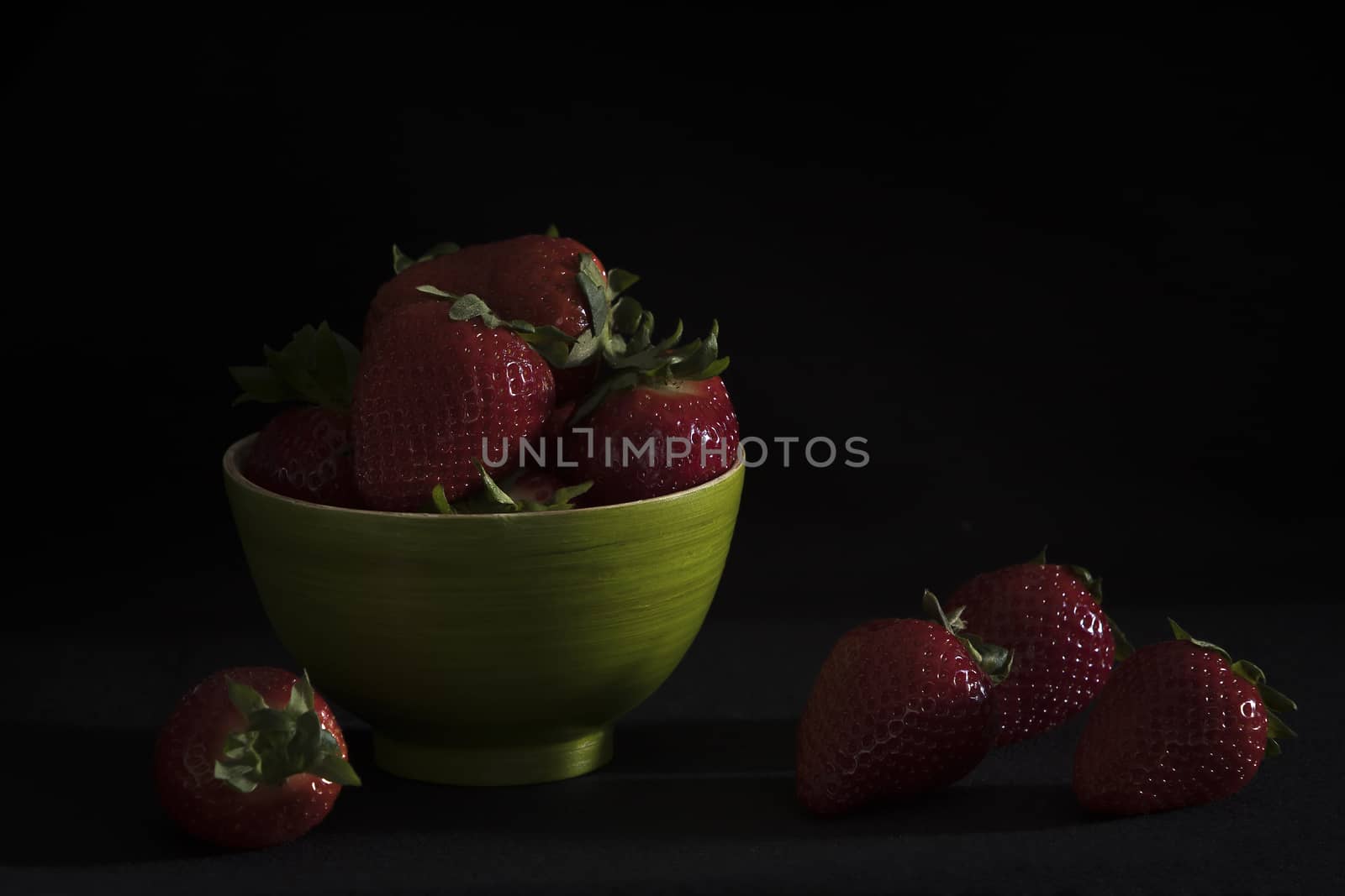 Strawberries in a green bamboo bowl on a black background