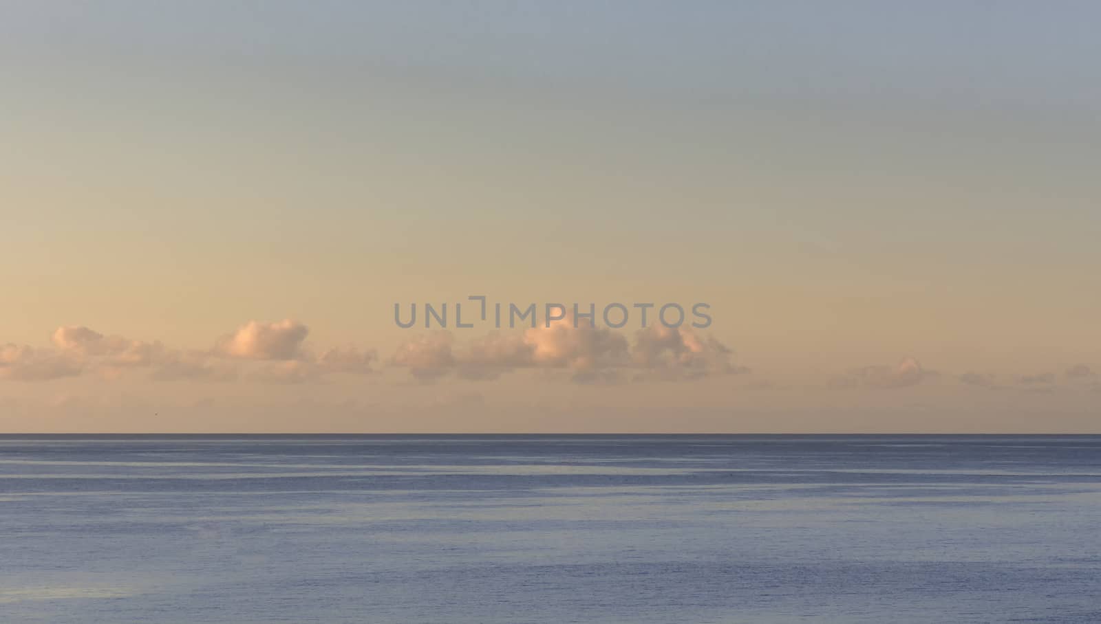 Sunset with a calm sea and small clouds on the horizon line