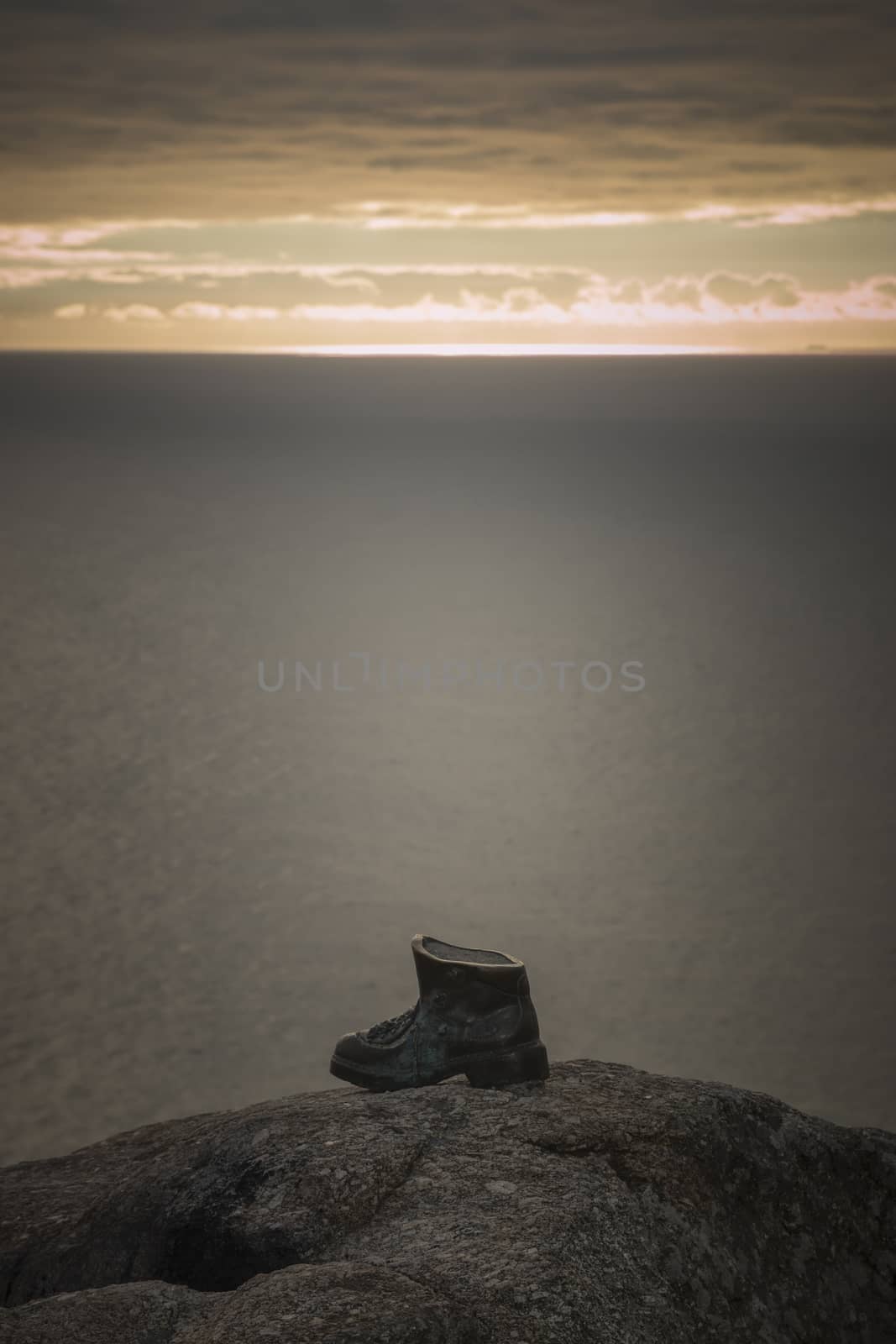 Sculpture of a bronze boot dedicated to the pilgrims of the Way of Saint James in Finisterre, Spain, at sunset