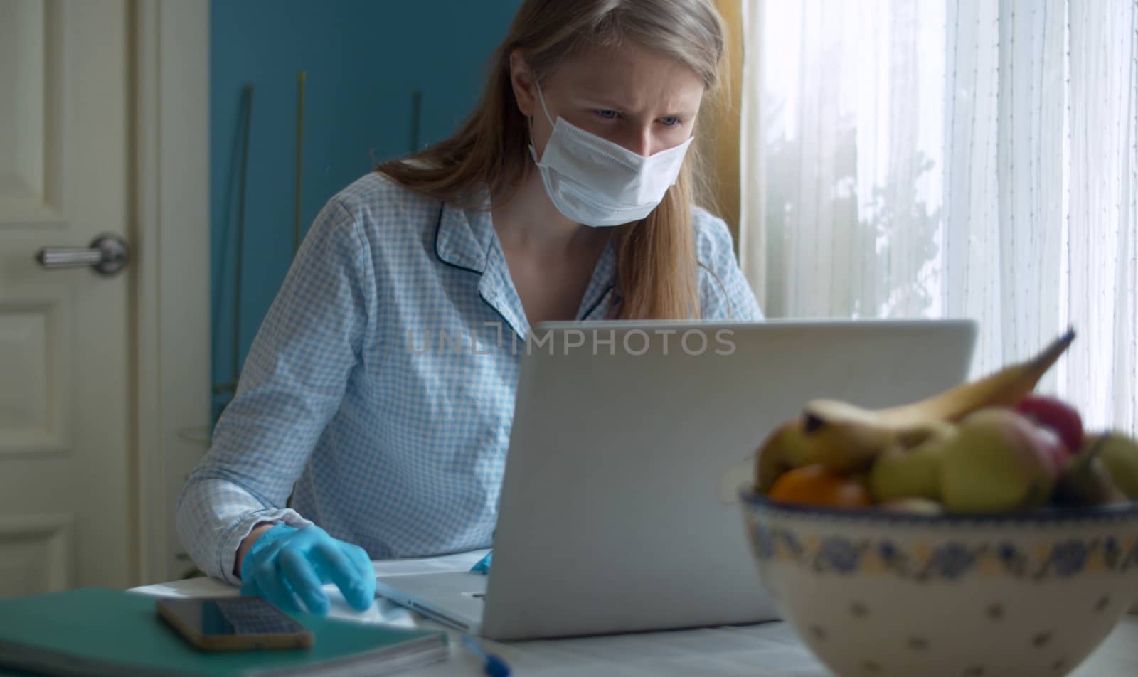 Portrait of a young woman working from home. Lady in a protective mask and gloves typing on a computer. Remote job. COVID-19 pandemic