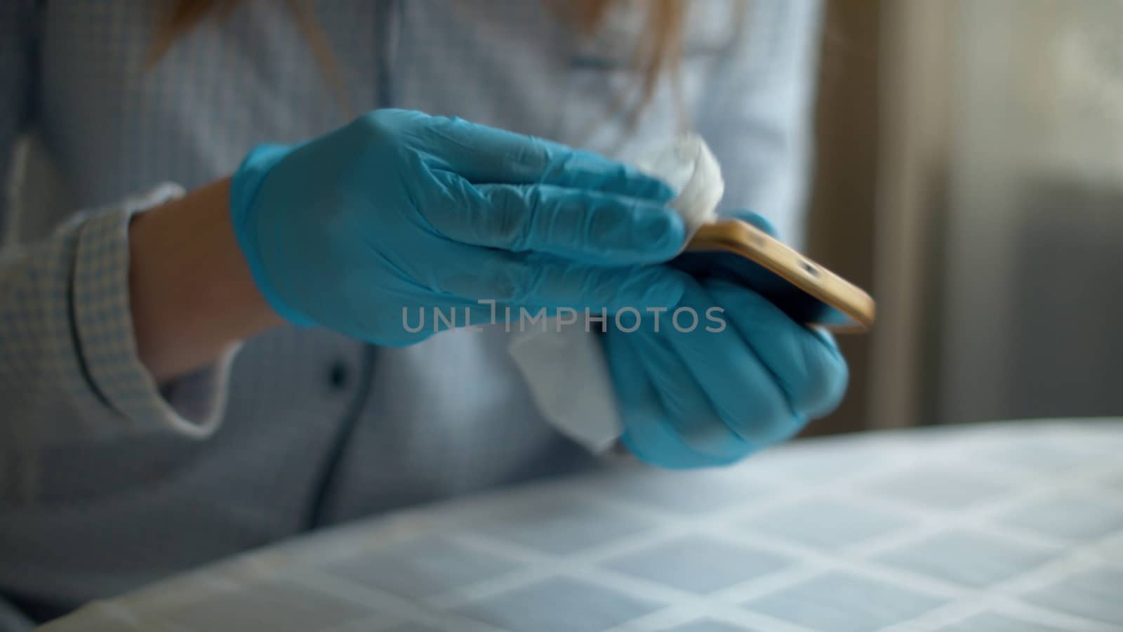 Close up hands in protective gloves cleaning smartphone with a disinfectant napkin. Hygiene during epidemic. Concept of safety life. Covid-19 pandemic