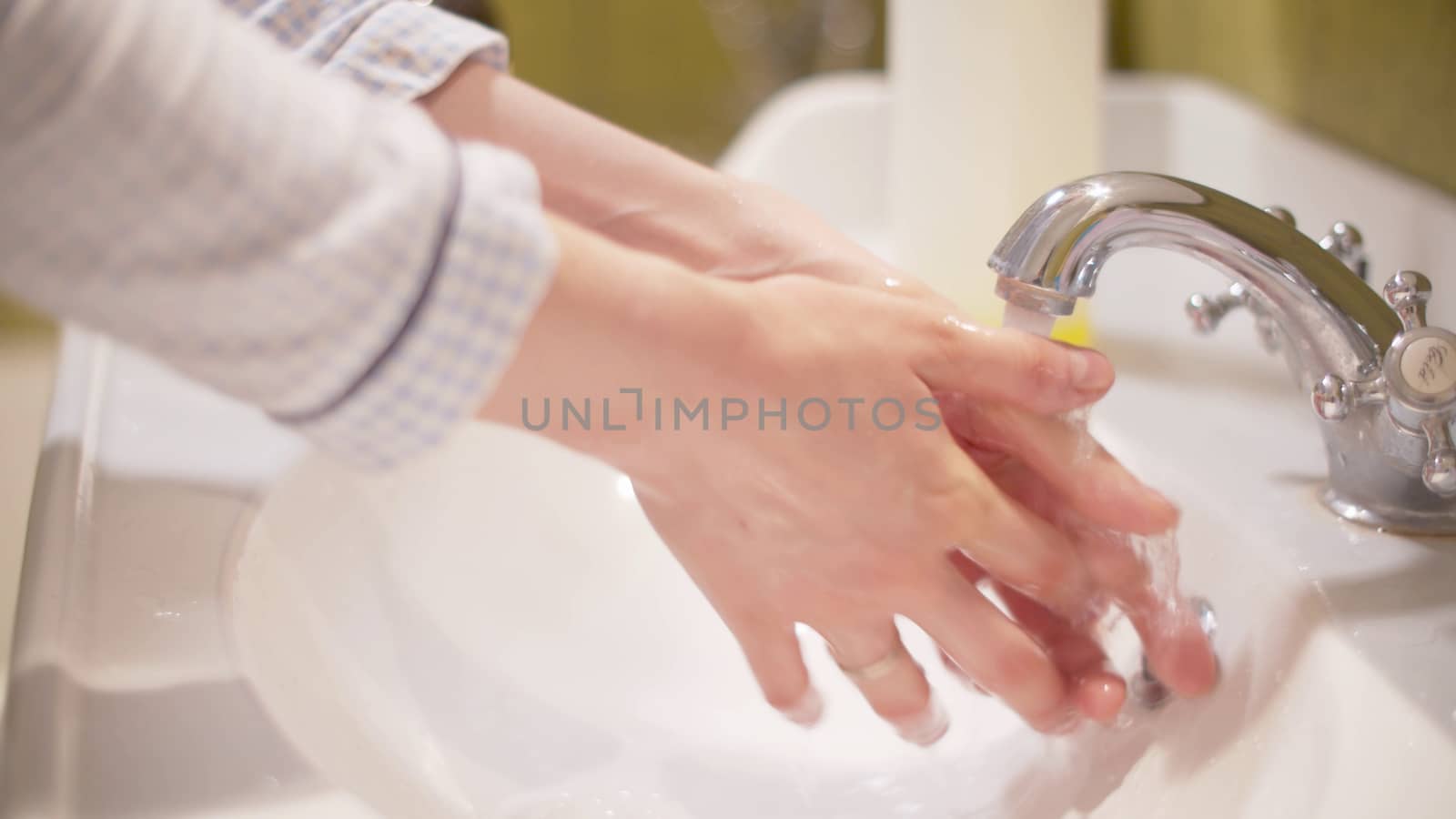 Woman scrupulously washing her hands. Close up female hands under water a bright bathroom. Hygiene during epidemic. Covid-19 pandemic