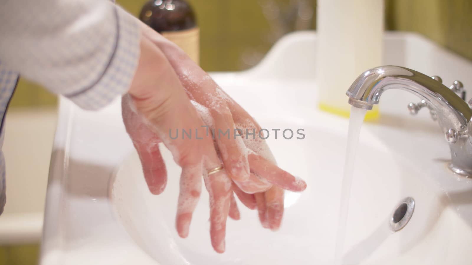 Woman scrupulously washing her hands. Close up female hands covered by soapy foam in a bright bathroom. Hygiene during epidemic. Covid-19 pandemic