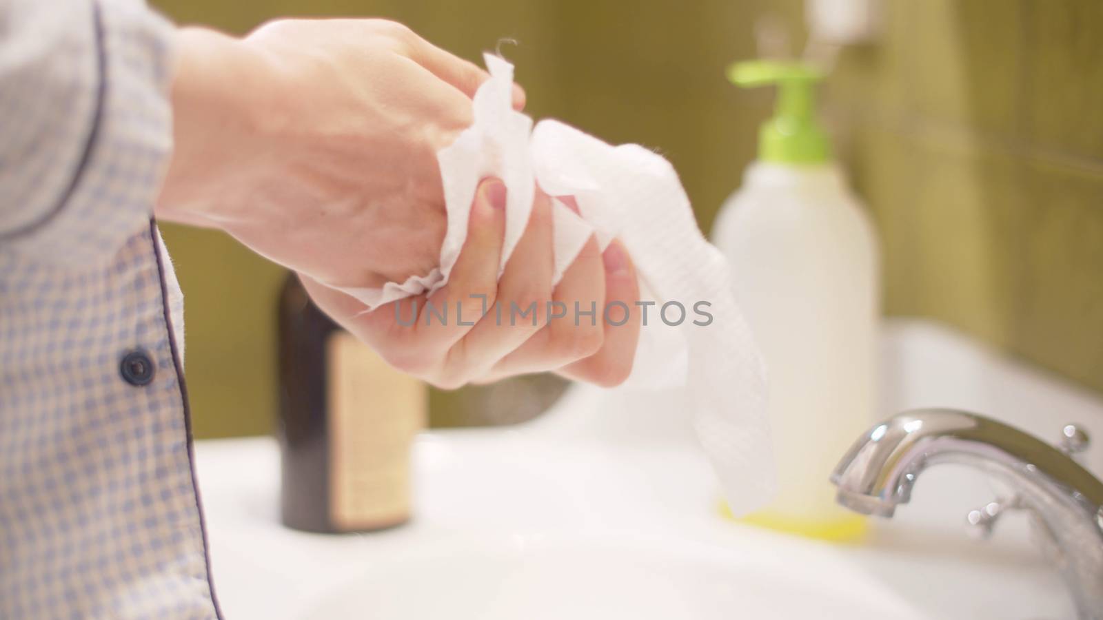 Young woman wiping hands with a disposable towel by Alize