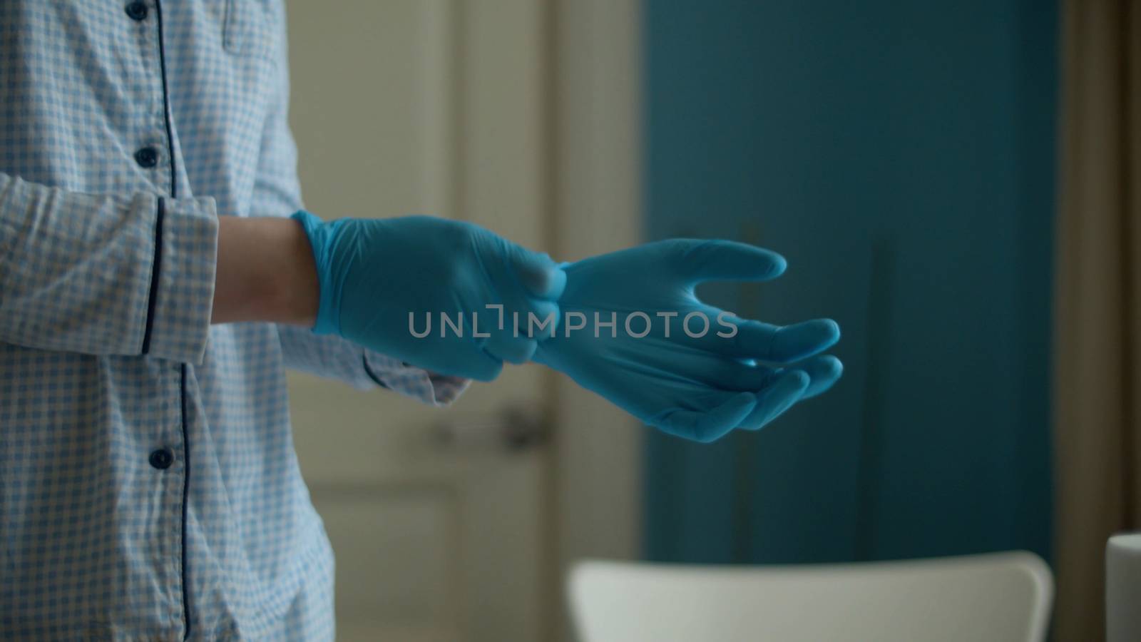 Close up hands of a young woman putting on a protective gloves in the bright room. Coronavirus epidemic. Concept of health and safety life. Covid-19 pandemic