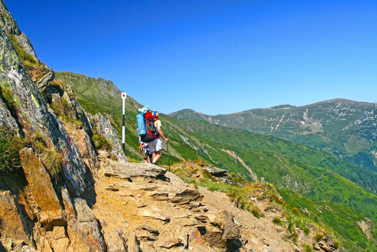 Summer landscape, hiking teens on mountain trail in Fagaras mountains.