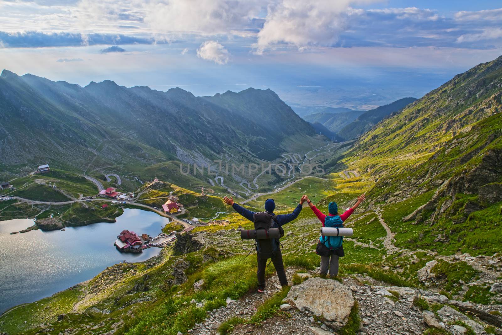 Young tourists with hands in the air in Fagaras mountains, summer landscape