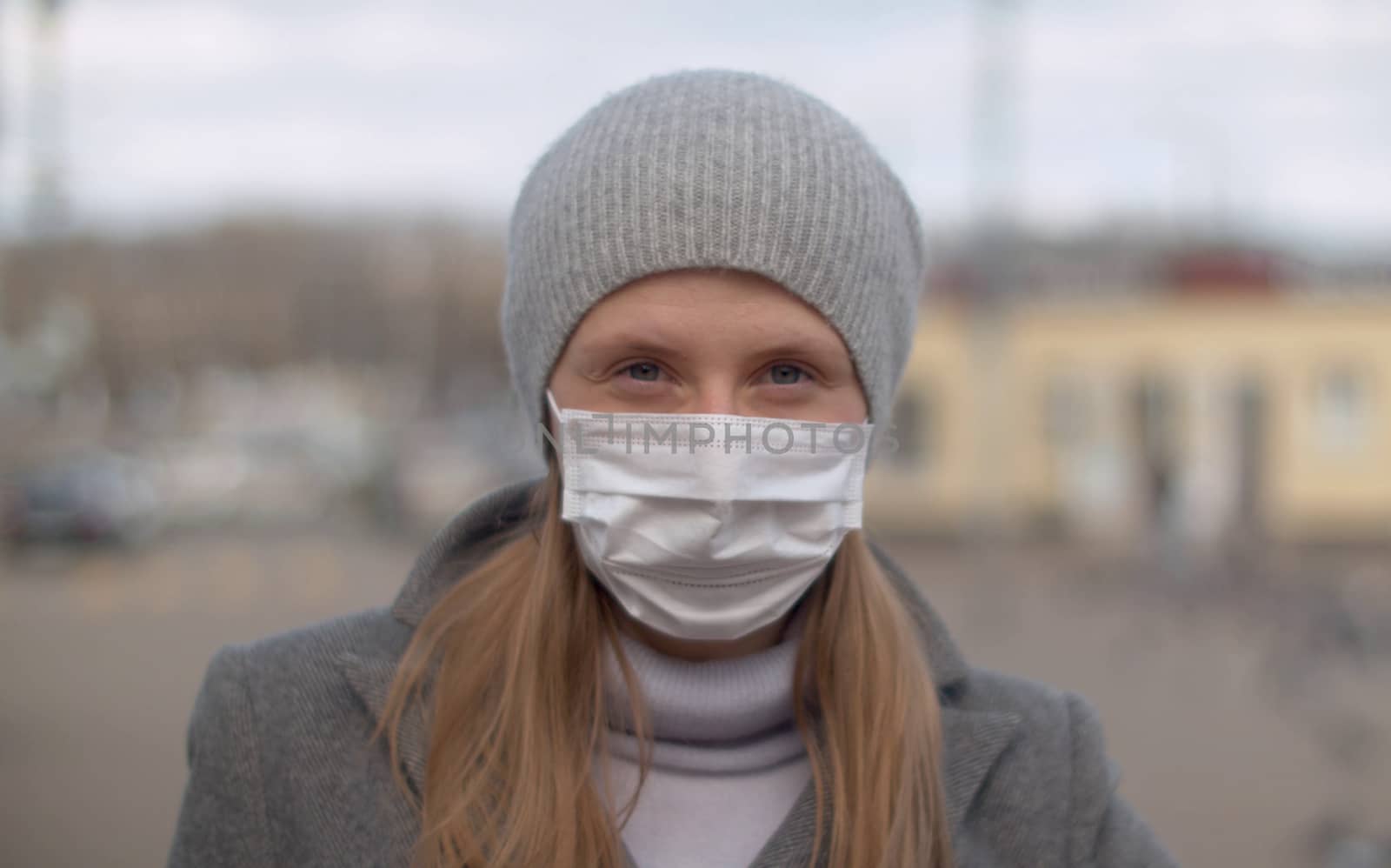 Close up portrait of a young handsome woman wearing protective mask outdoors on the blurry city background. Protect yourself and your loved ones. Covid-19 pandemic