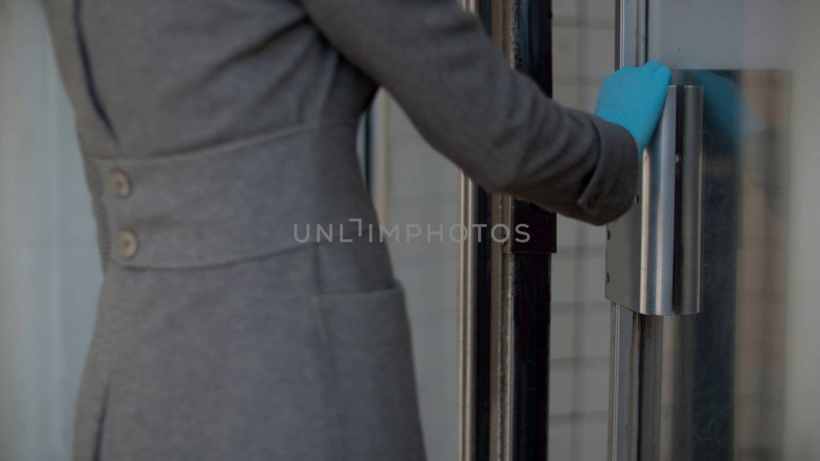 Woman in protective glove opening the door to the subway station. Coronavirus epidemic in the city. Healthy and safety lifestyle concept. Covid-19 pandemic