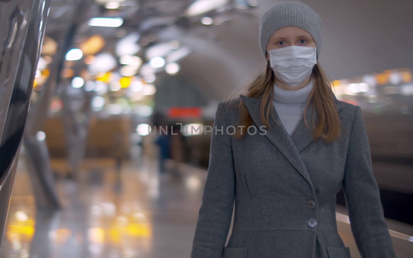Portrait of young woman in protective mask standing on the subway station. Beautiful blurry background. Healthy and safety lifestyle concept. Covid-19 pandemic