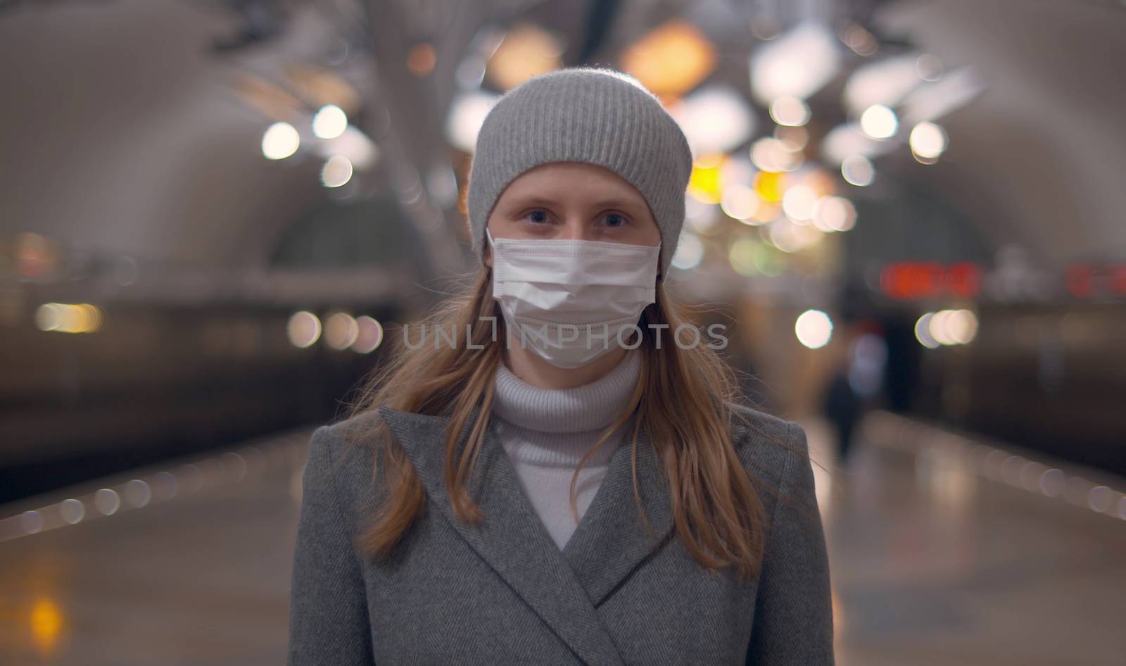 Portrait of young woman in protective mask standing on the subway station. Beautiful blurry background. Healthy and safety lifestyle concept. Covid-19 pandemic