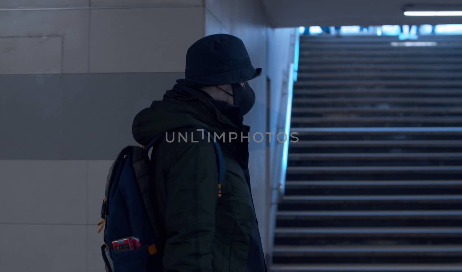 Man in a protective mask walking in the underground crossing. Coronavirus epidemic in the city. Safety life concept. COVID-19 pandemic