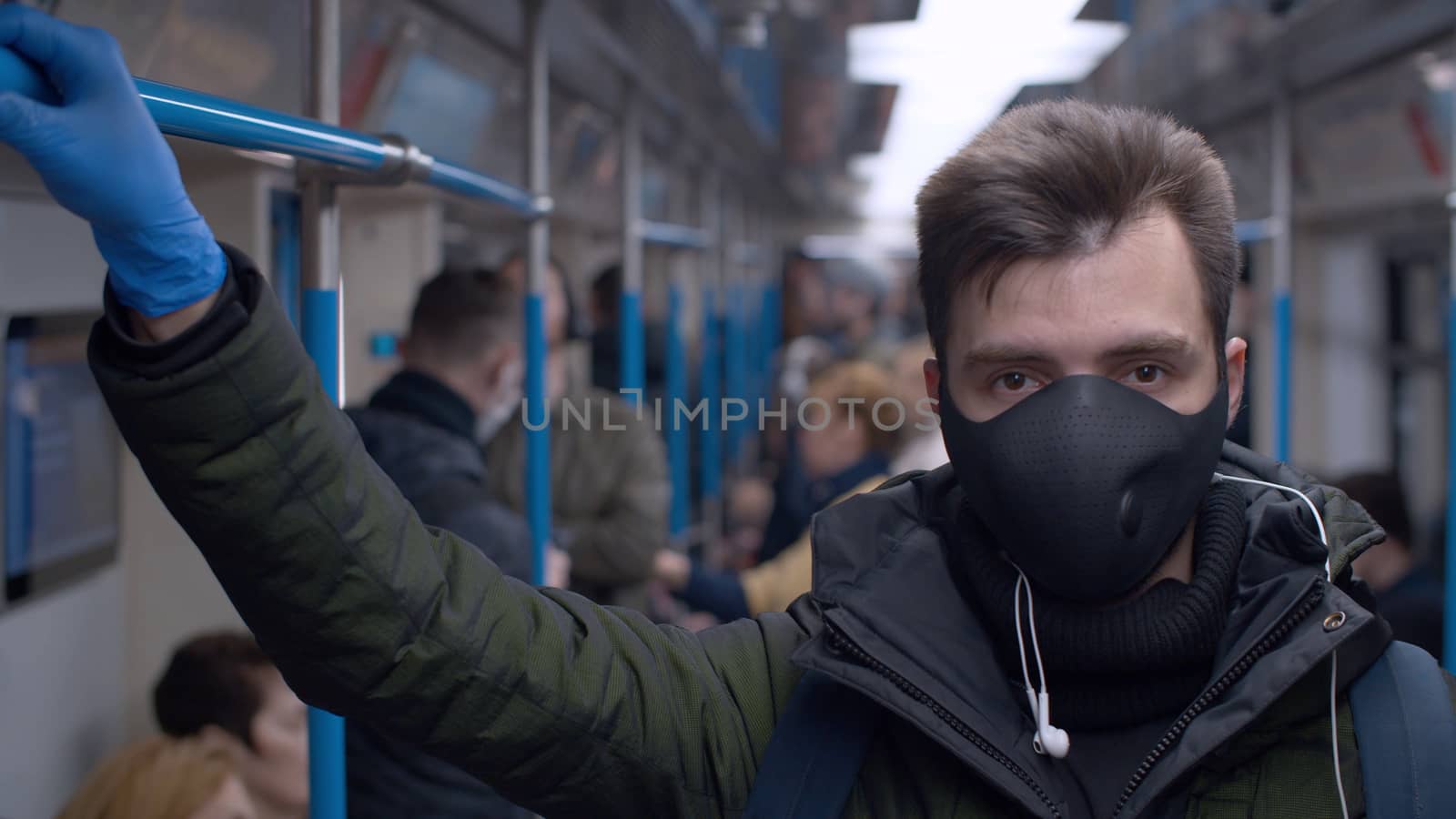 Close up portrait of a young man in a reusable protective mask in subway train. Coronavirus epidemic in big city. Safety life concept. COVID-19 pandemic