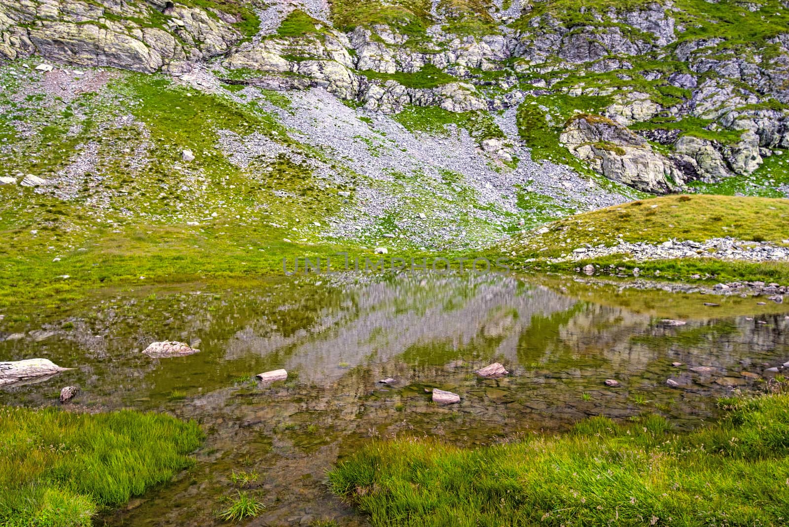 Pond with clear water in rocky mountain, summer view in Fagaras Mountains.