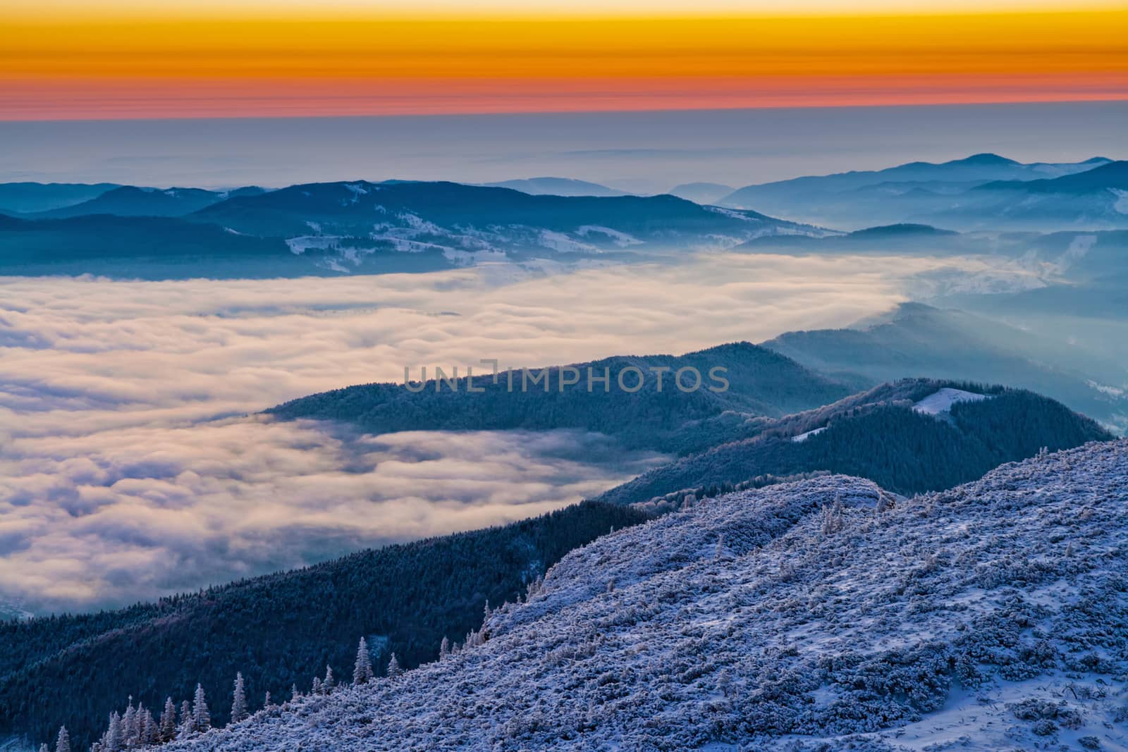 Winter sunrise from mountain top,mist in the valley in Romanian Carpathians.