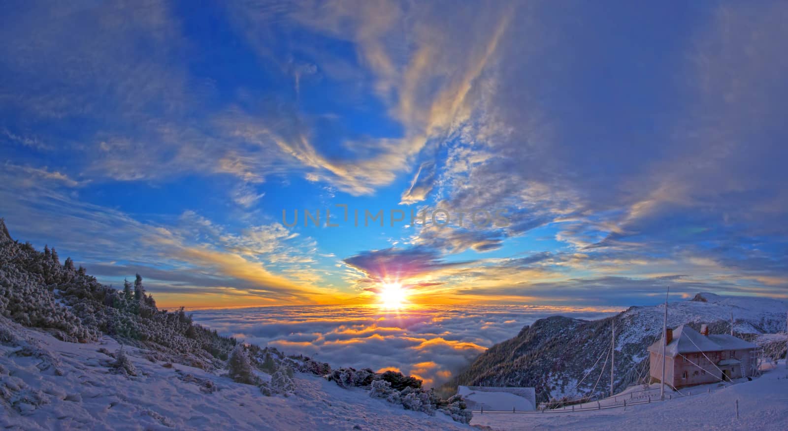 Frozen chalet on the mountain, sunrise landscape with low clouds on valley