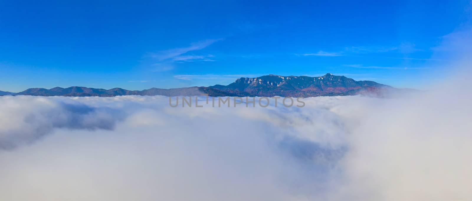 Flying over mist clouds, sunrise mountain landscape with low clouds