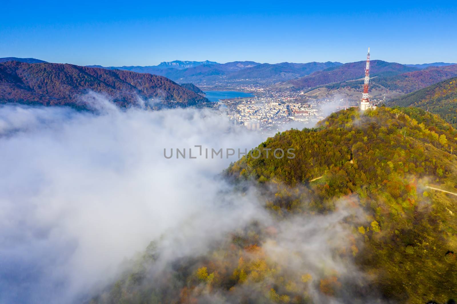 Aerial view of mountain city covered by fog, autumn landscape in Romania, Piatra Neamt downtown