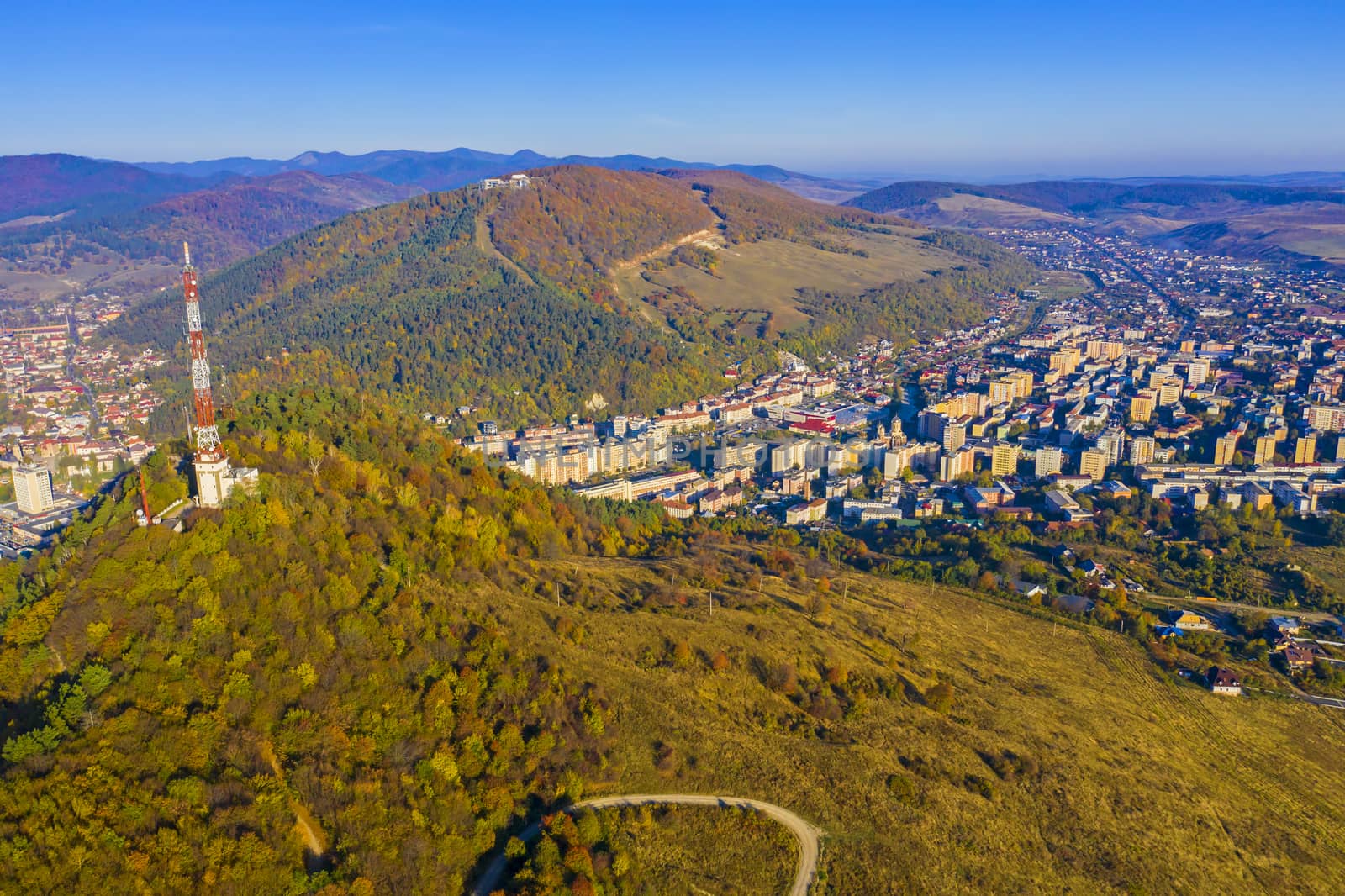 Aerial view of antenna tower and Piatra Neamt city in the valley, autumn landscape.