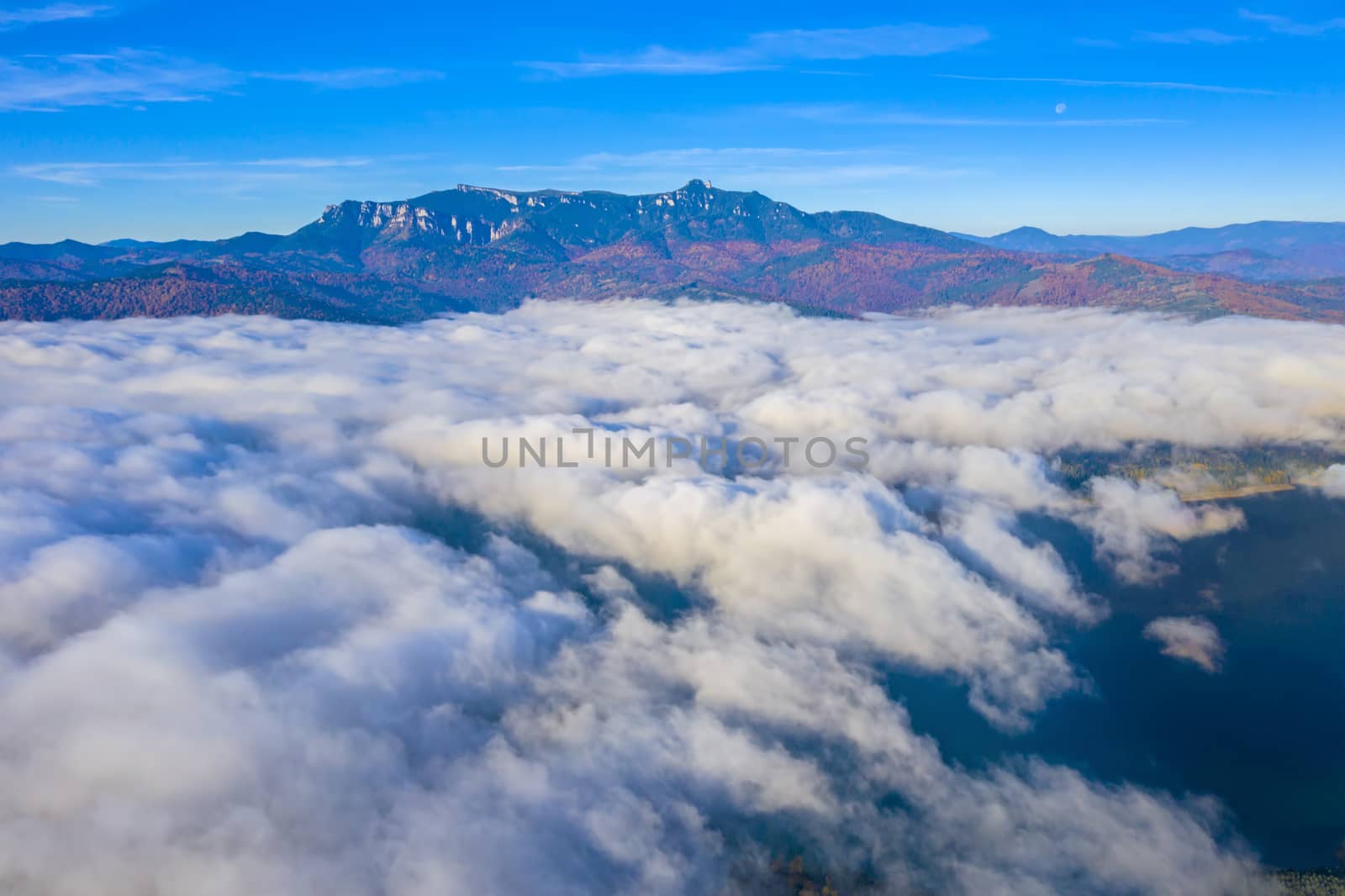 Flying over mist clouds in Romanian Carpathians. clouds over the lake and autumn mountain view