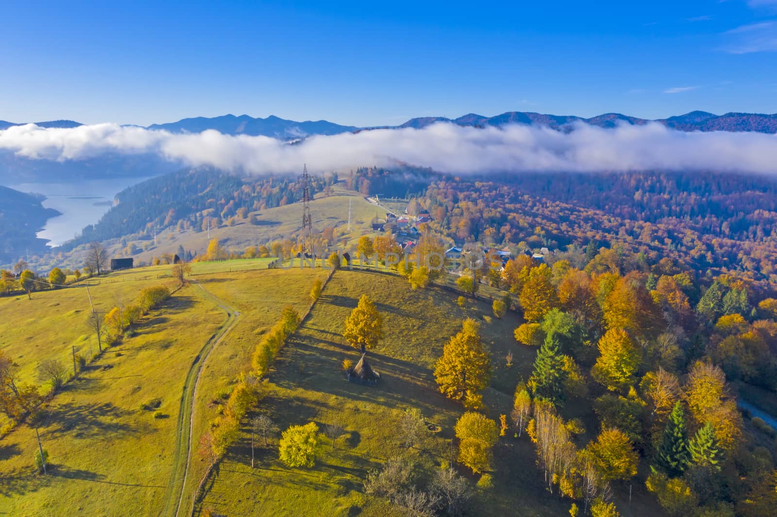 Aerial view of autumn hill and forest with cloud floating over the lake in Romanian Carpathians