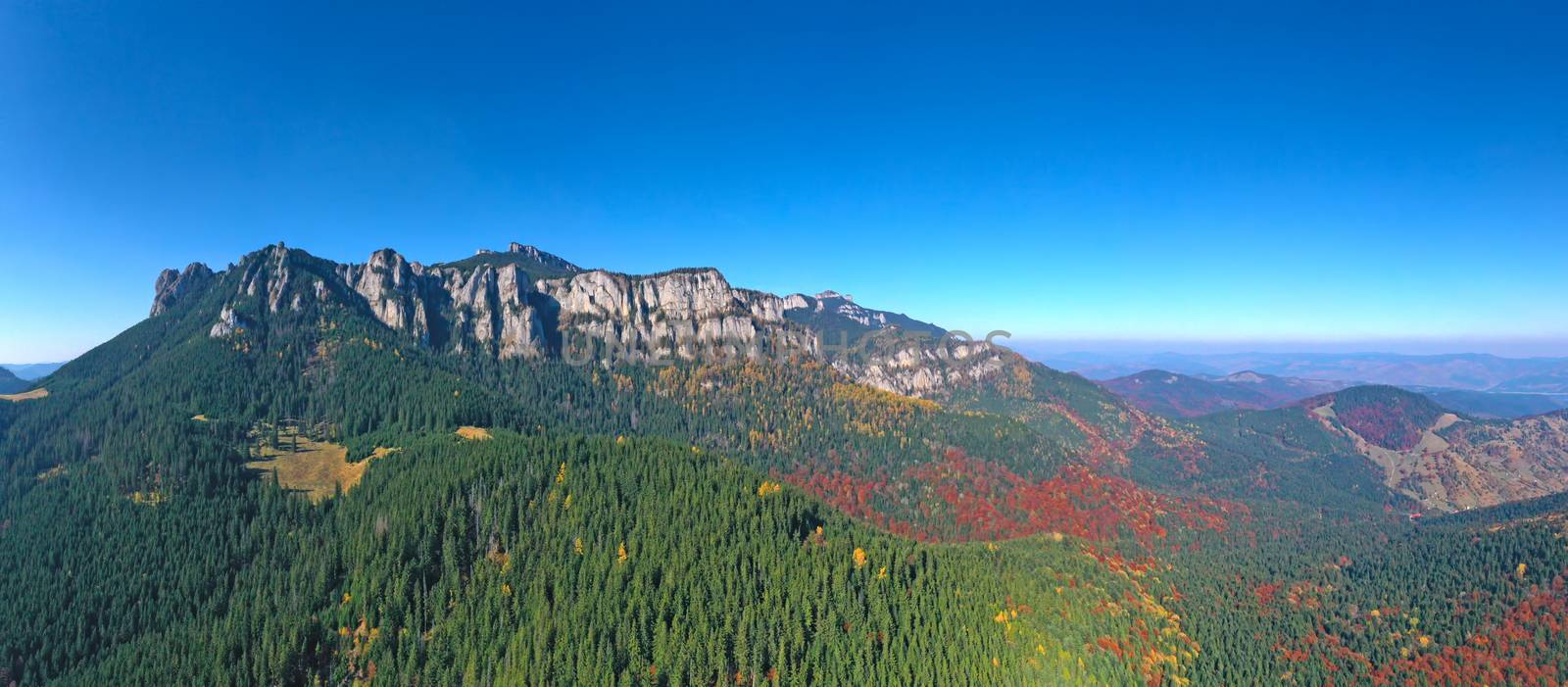 Aerial view of rocky mountain and colored forest in Romanian Carpathians, beautiful autumn landscape