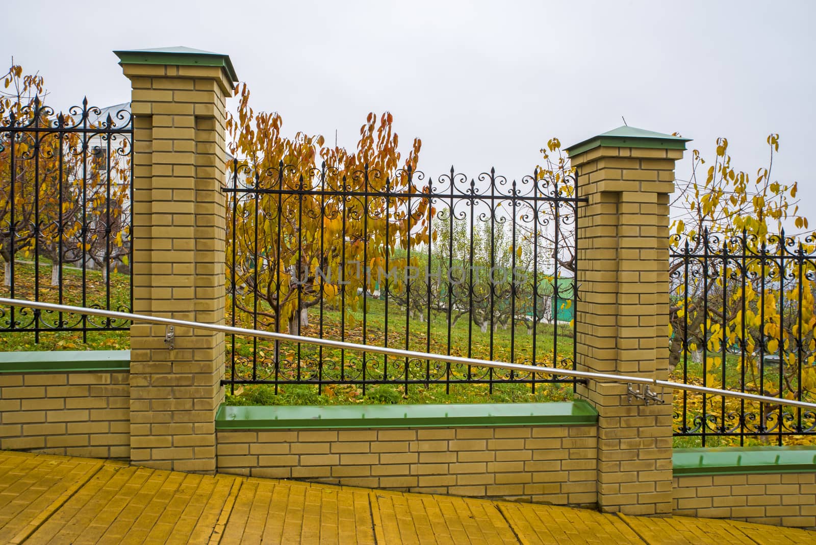 Metal fence and orchard in a autumn landscape