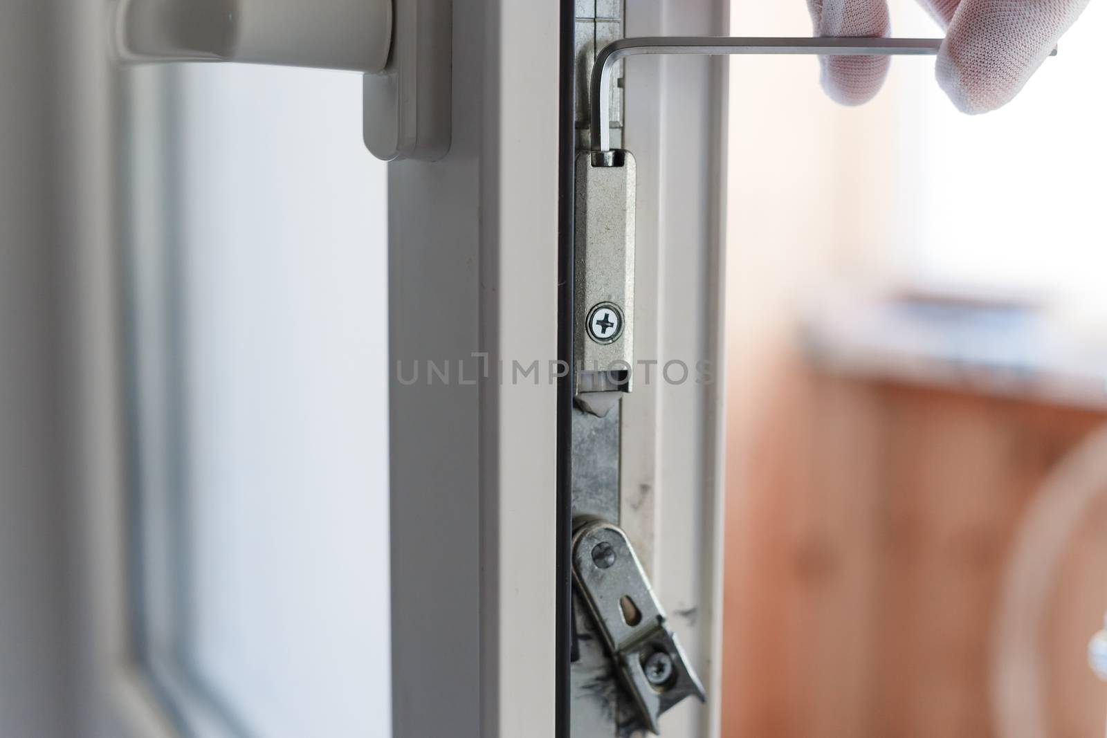 Man's hand makes adjustment of hardware of the uPVC door mechanism with an allen key