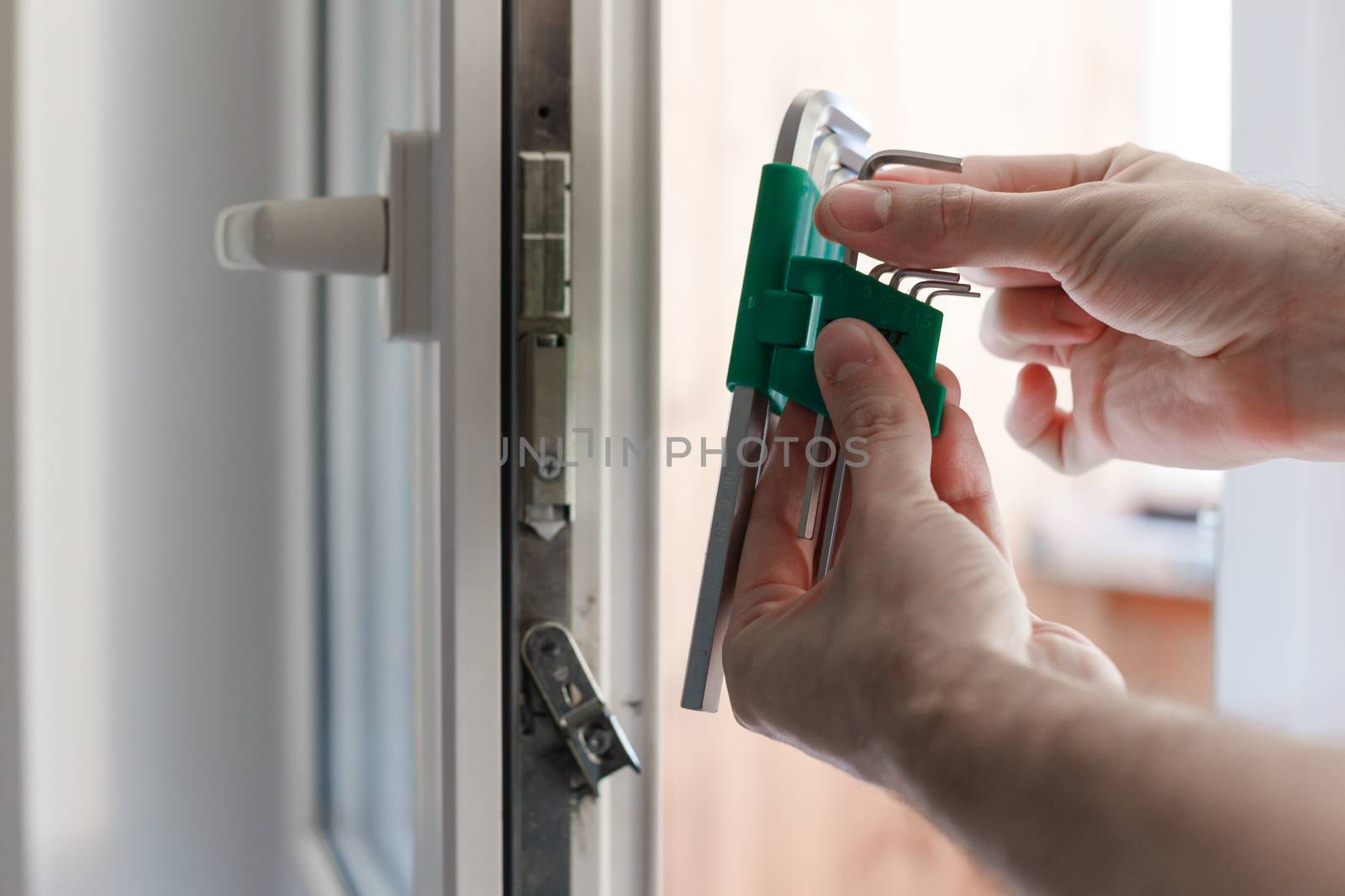 Man's hand choose allen key for adjustment of hardware of the uPVC door mechanism by vladdeep