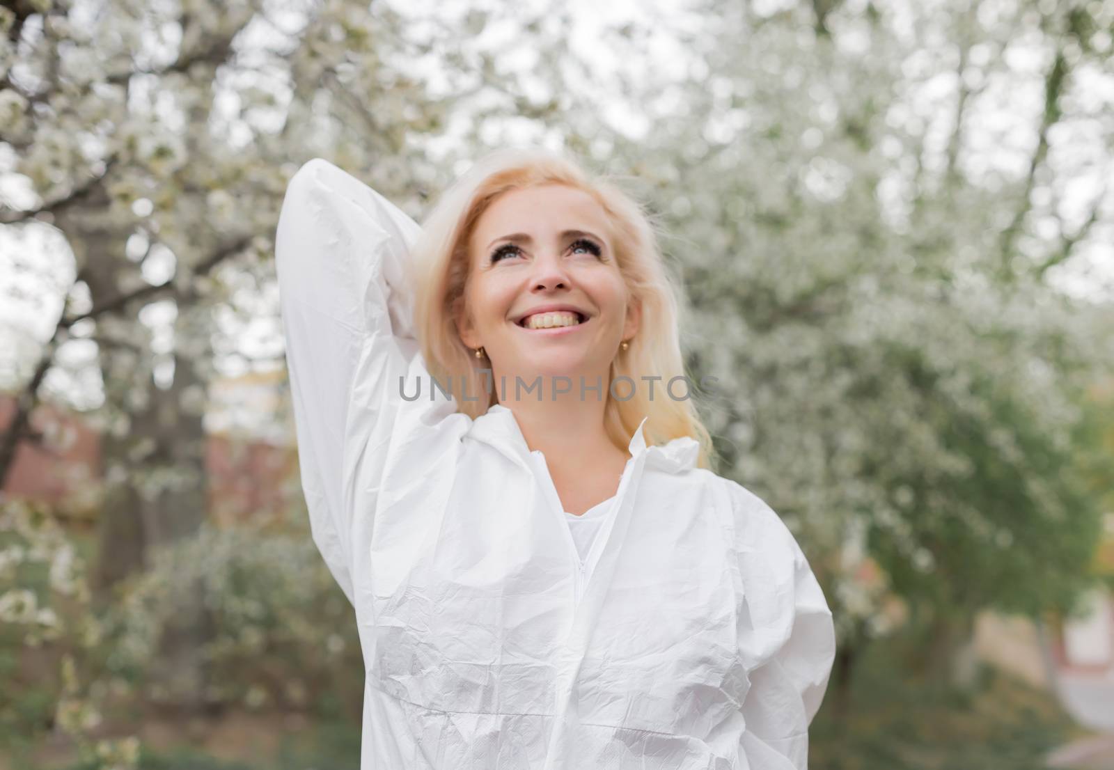 Happy woman in white protective suit among spring garden