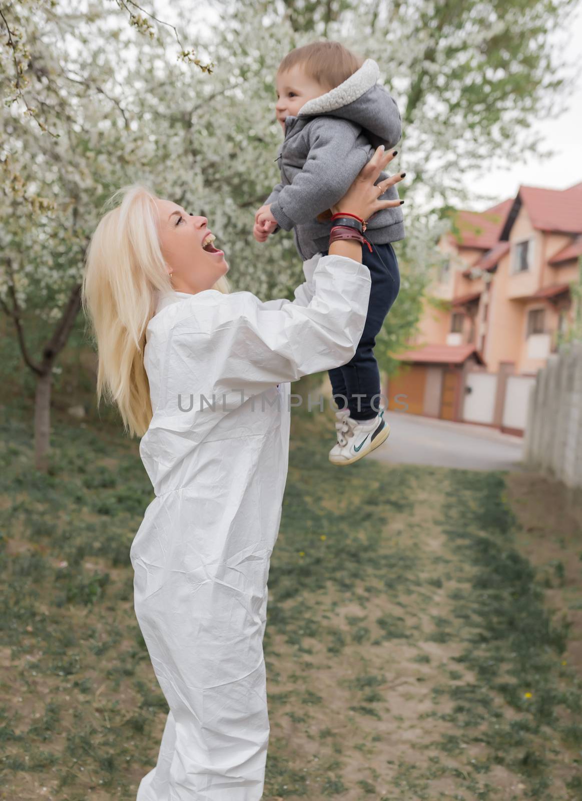 Happy woman in white protective suit meeting baby boy