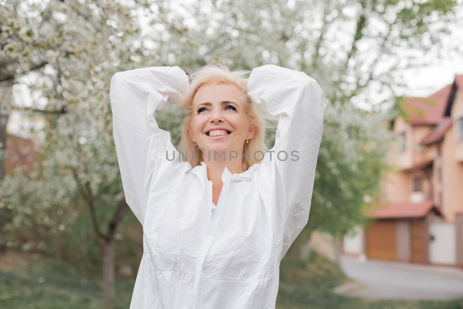 Happy woman in white protective suit among spring garden