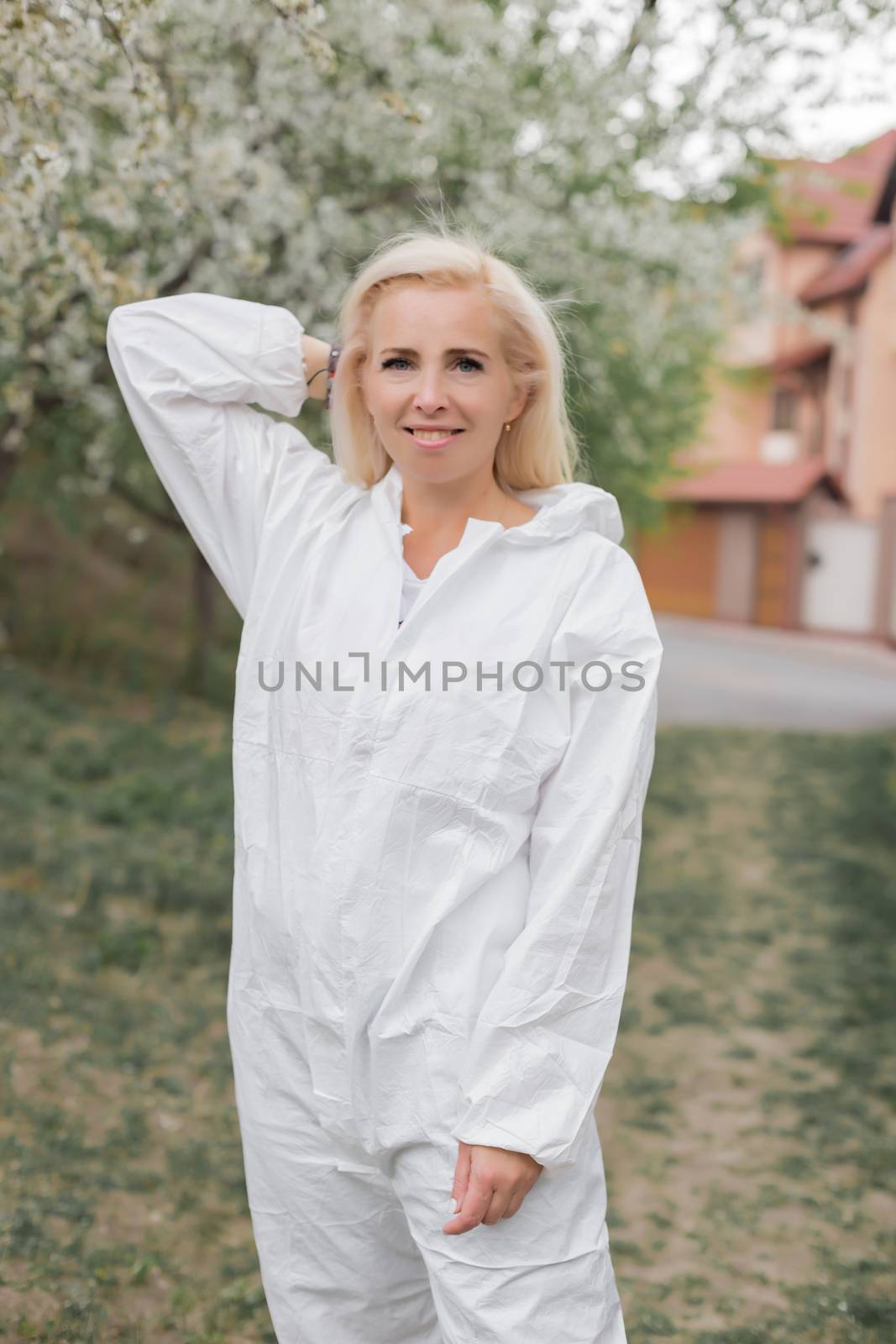 Happy woman in white protective suit among garden
