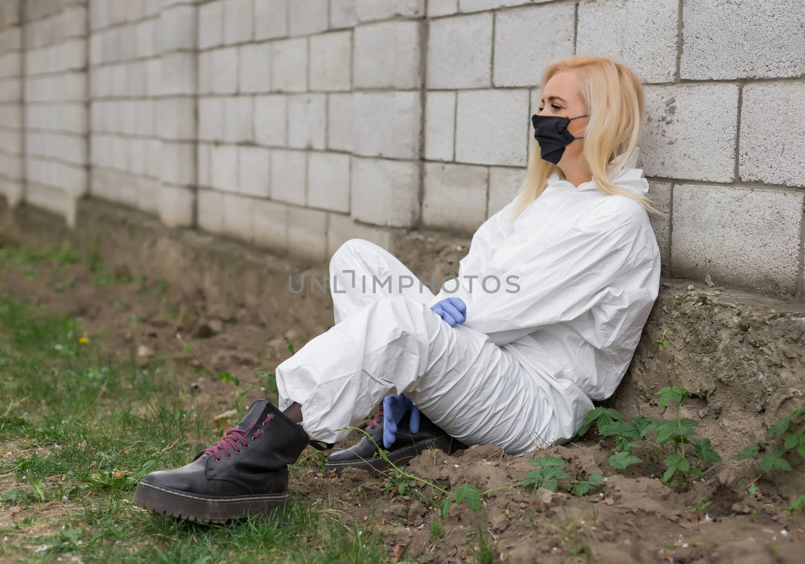 Woman in black mask, white protective suit sitting
