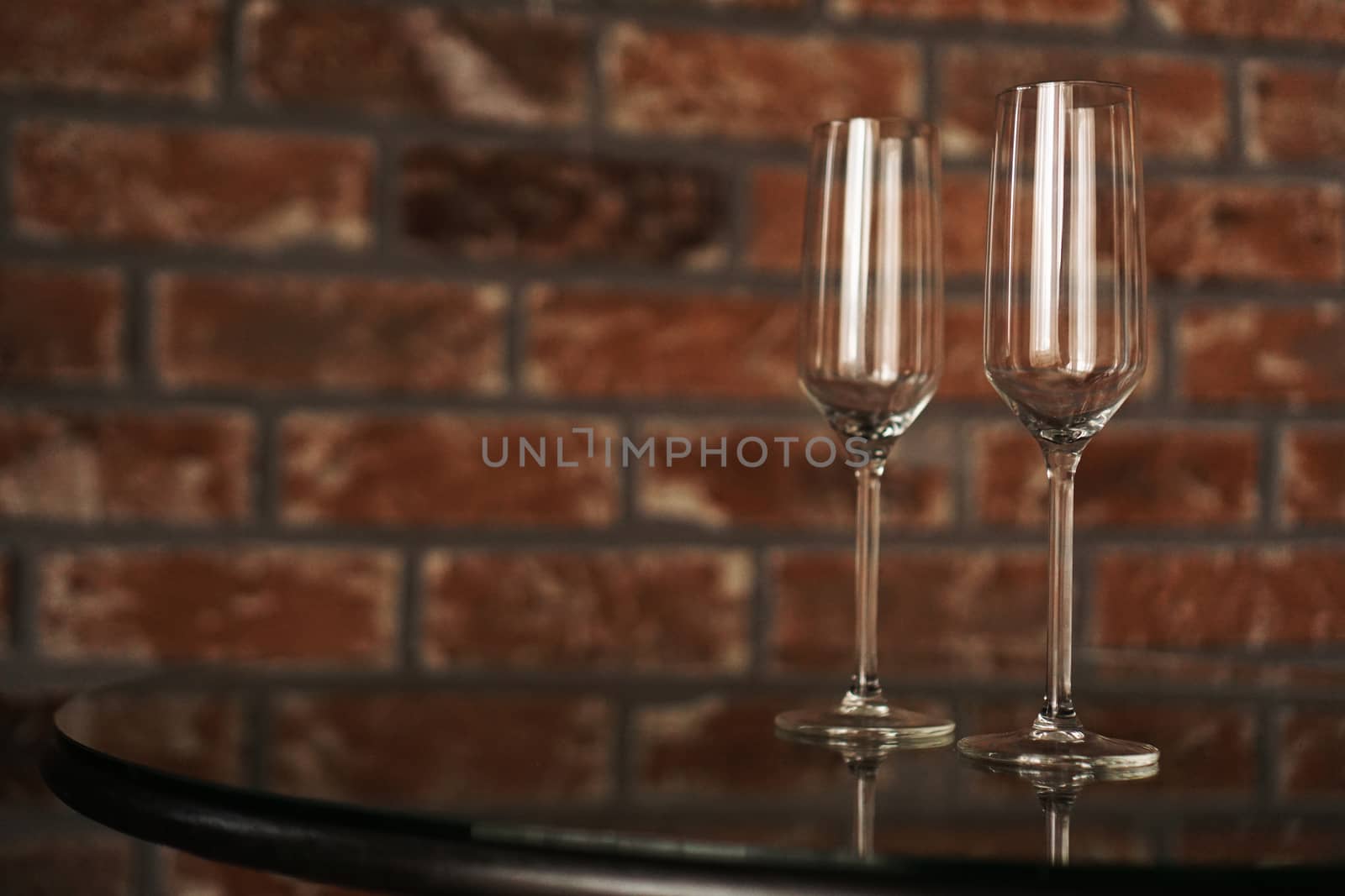 Two glasses on a blurred background of a brick wall. Romantic evening, date. Place for the inscription.