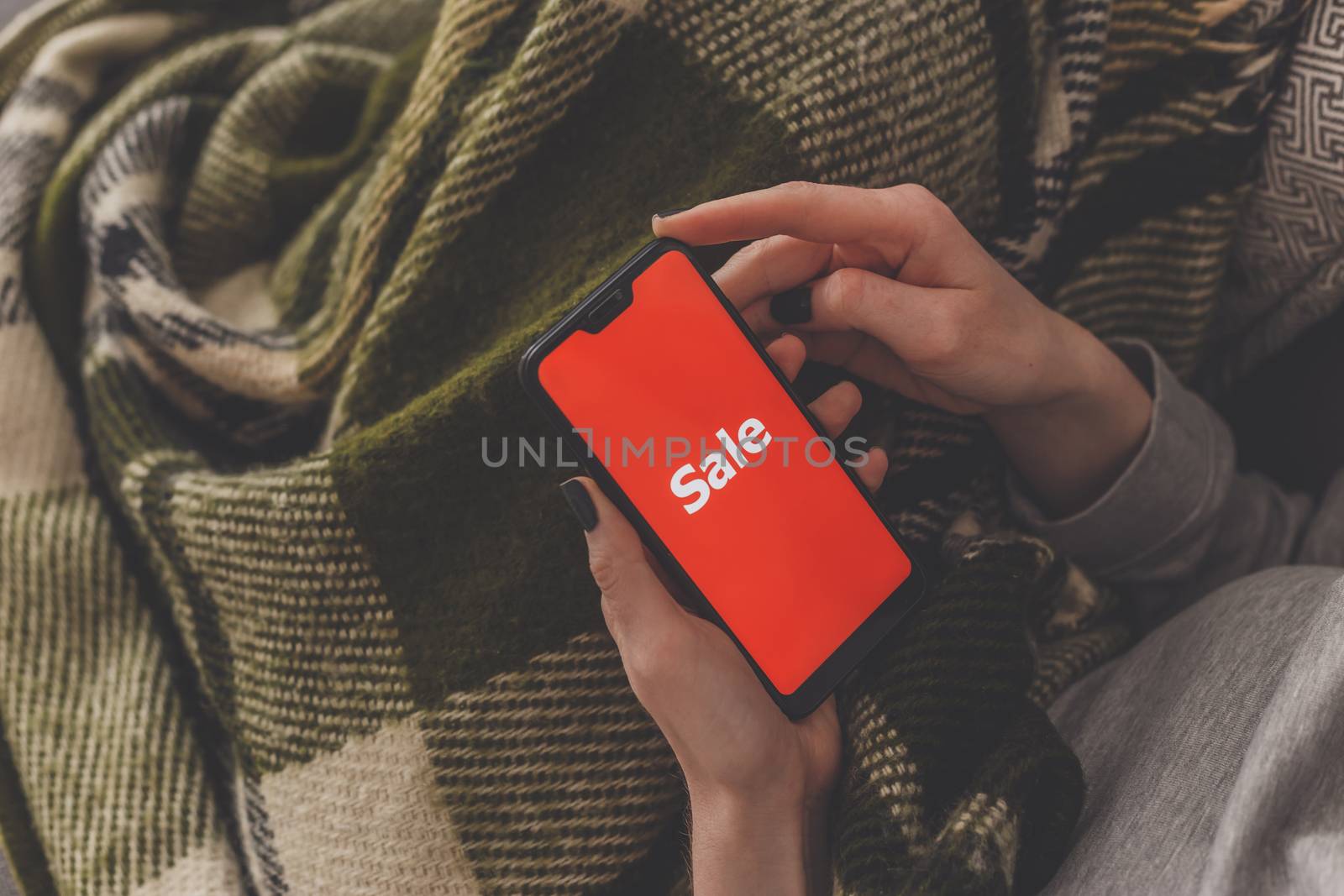 Sale on the phone screen. Woman holds a phone in his hand and sees the inscription sale. Online shopping without leaving home during quarantine. Black friday sale.