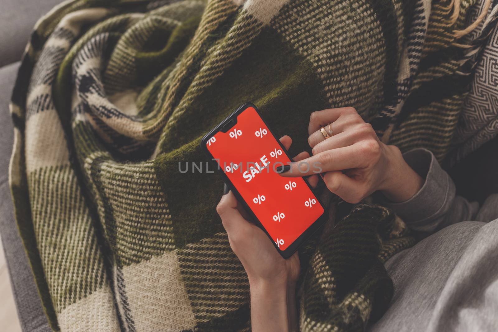 Sale on the phone screen. Woman holds a phone in his hand and sees the inscription sale. Online shopping without leaving home during quarantine. Black friday sale.