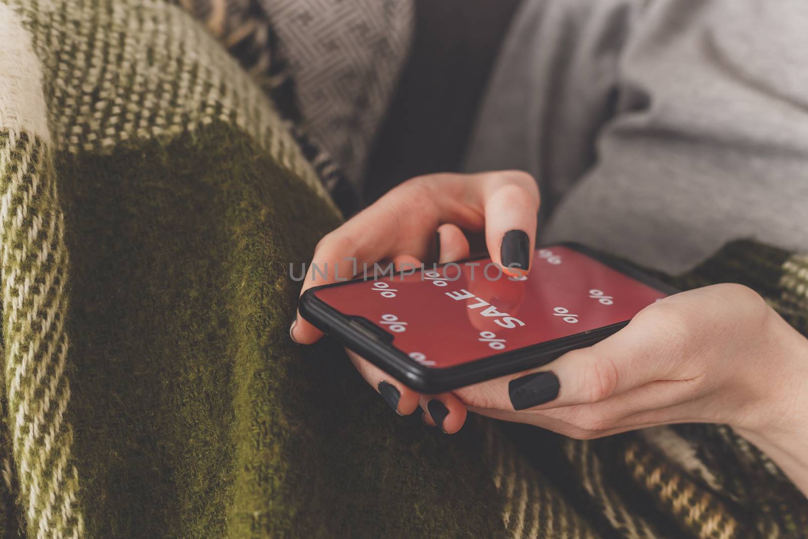 Sale on the phone screen. Woman holds a phone in his hand and sees the inscription sale. Online shopping without leaving home during quarantine. Black friday sale by vladdeep