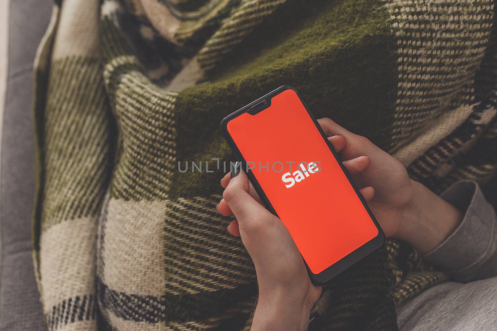 Sale on the phone screen. Woman holds a phone in his hand and sees the inscription sale. Online shopping without leaving home during quarantine. Black friday sale.