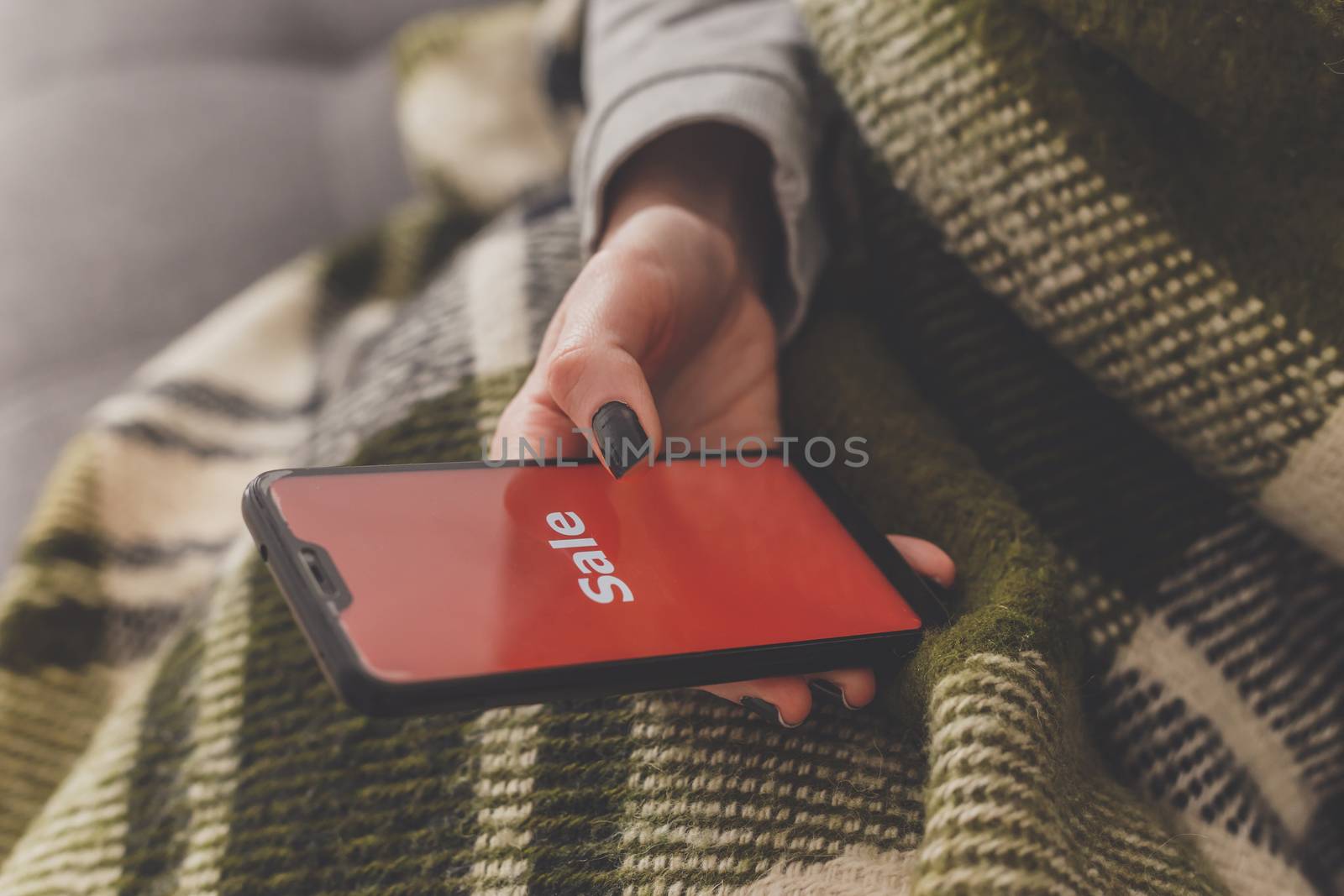 Sale on the phone screen. Woman holds a phone in his hand and sees the inscription sale. Online shopping without leaving home during quarantine. Black friday sale by vladdeep