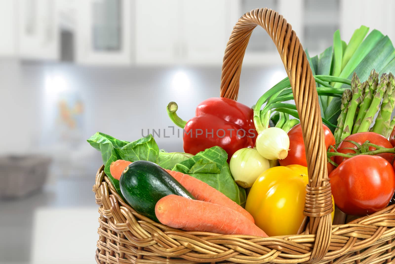 Healthy eating concept - basket full of varied fresh vegetables on a blurred background of the kitchen.