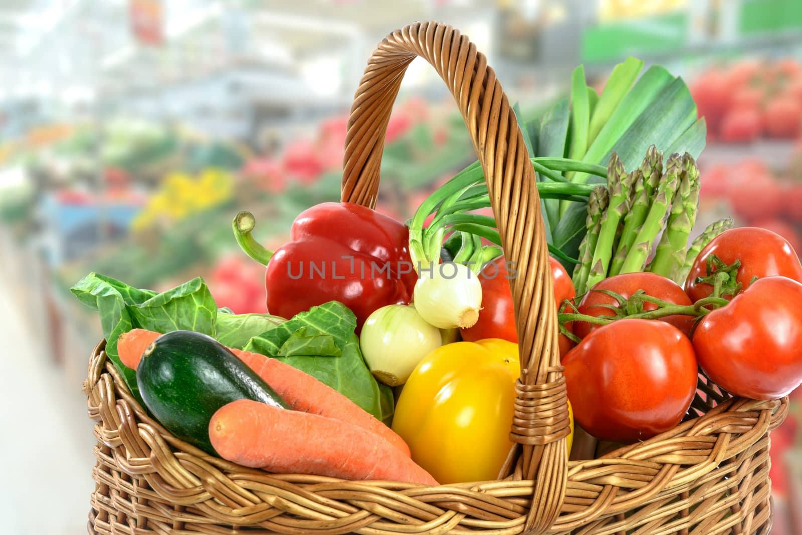 Green Grocery shopping concept image - basket full of varied fresh vegetables on a blurred supermarket background.