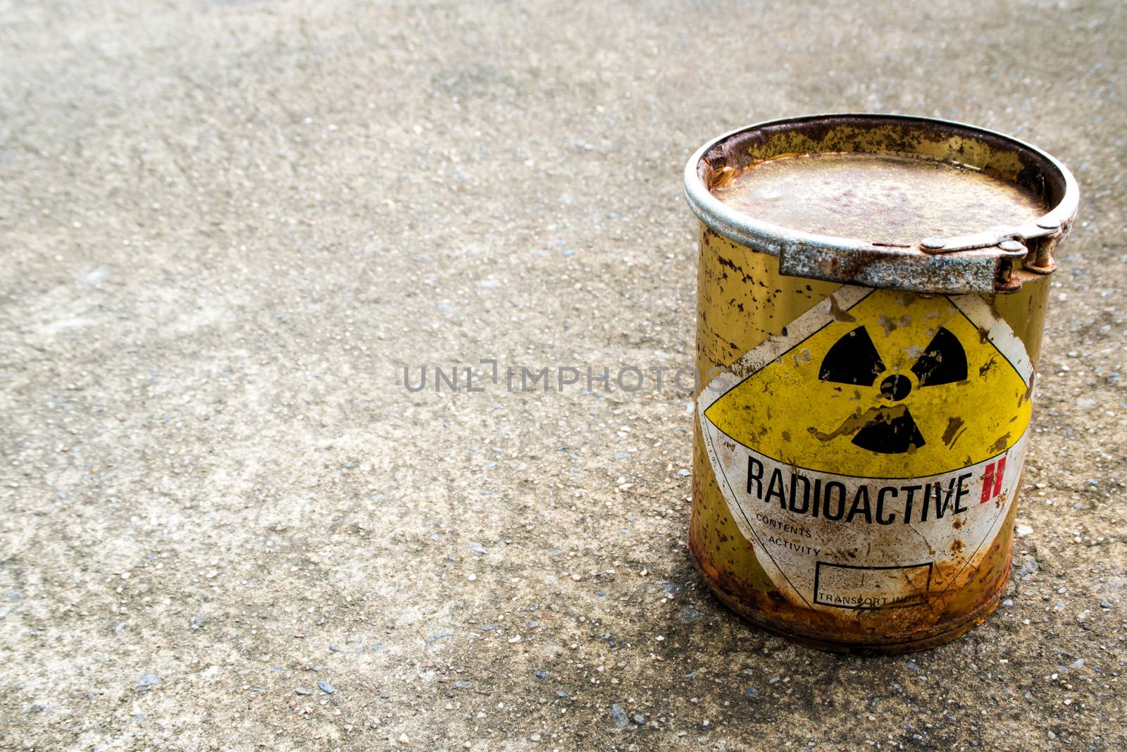 Radiation warning sign on rusty package of radioactive material container on the rough concrete floor