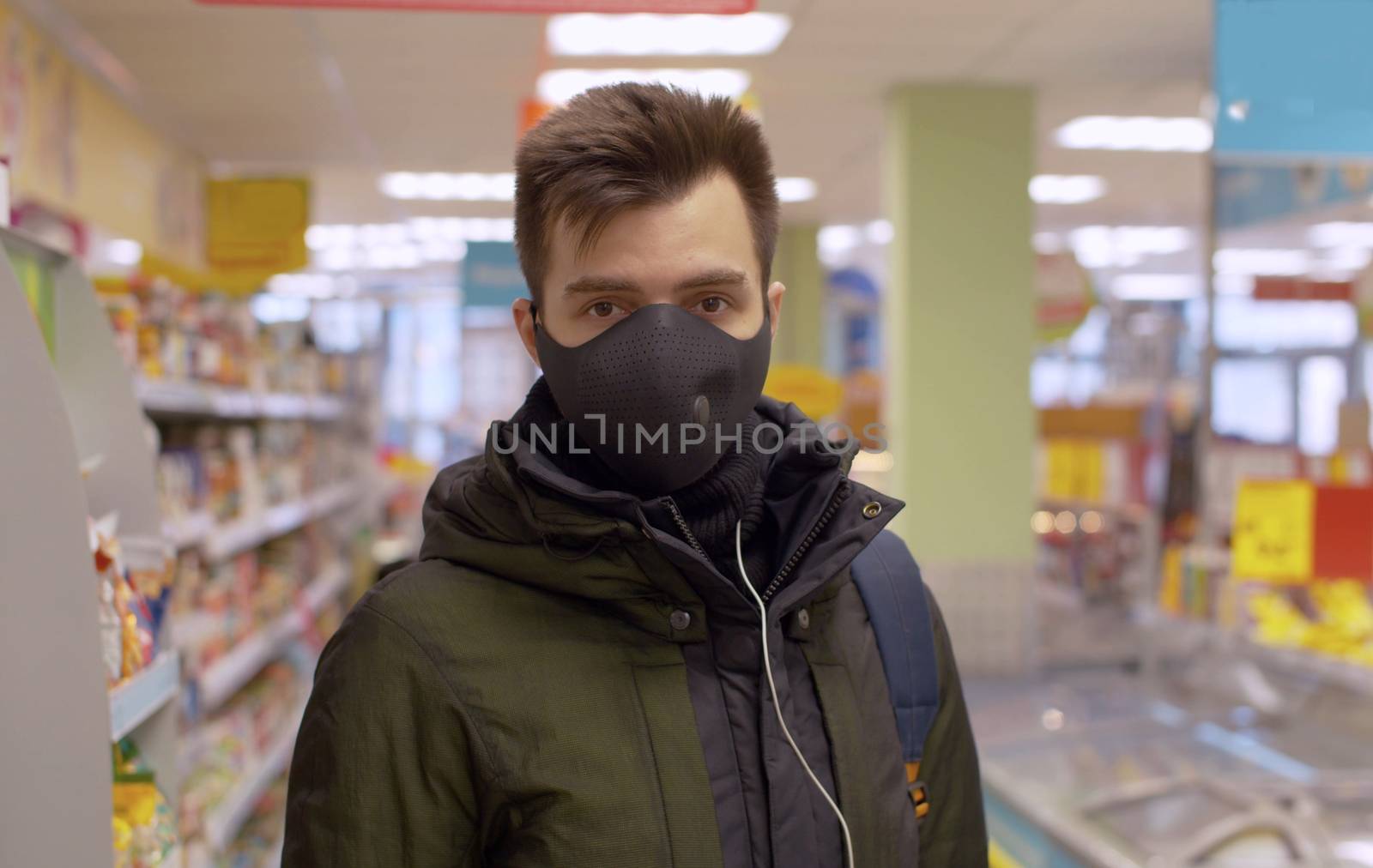 A man in a protective mask standing in the supermarket with a discouraged look. Coronavirus epidemic in the city. COVID-19 pandemic